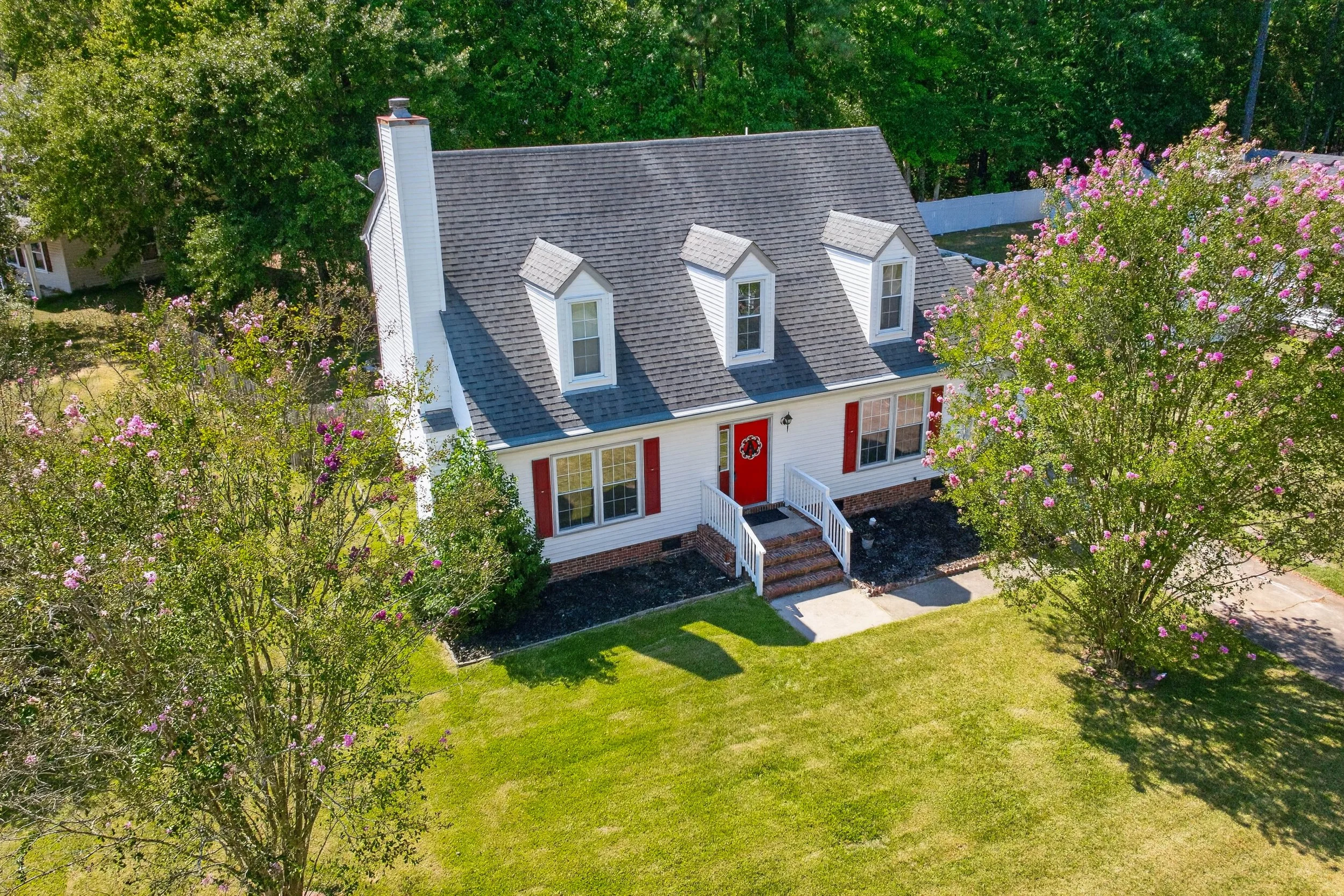 An elevated front view shows the home, attached garage and surrounding corner-lot lawn.