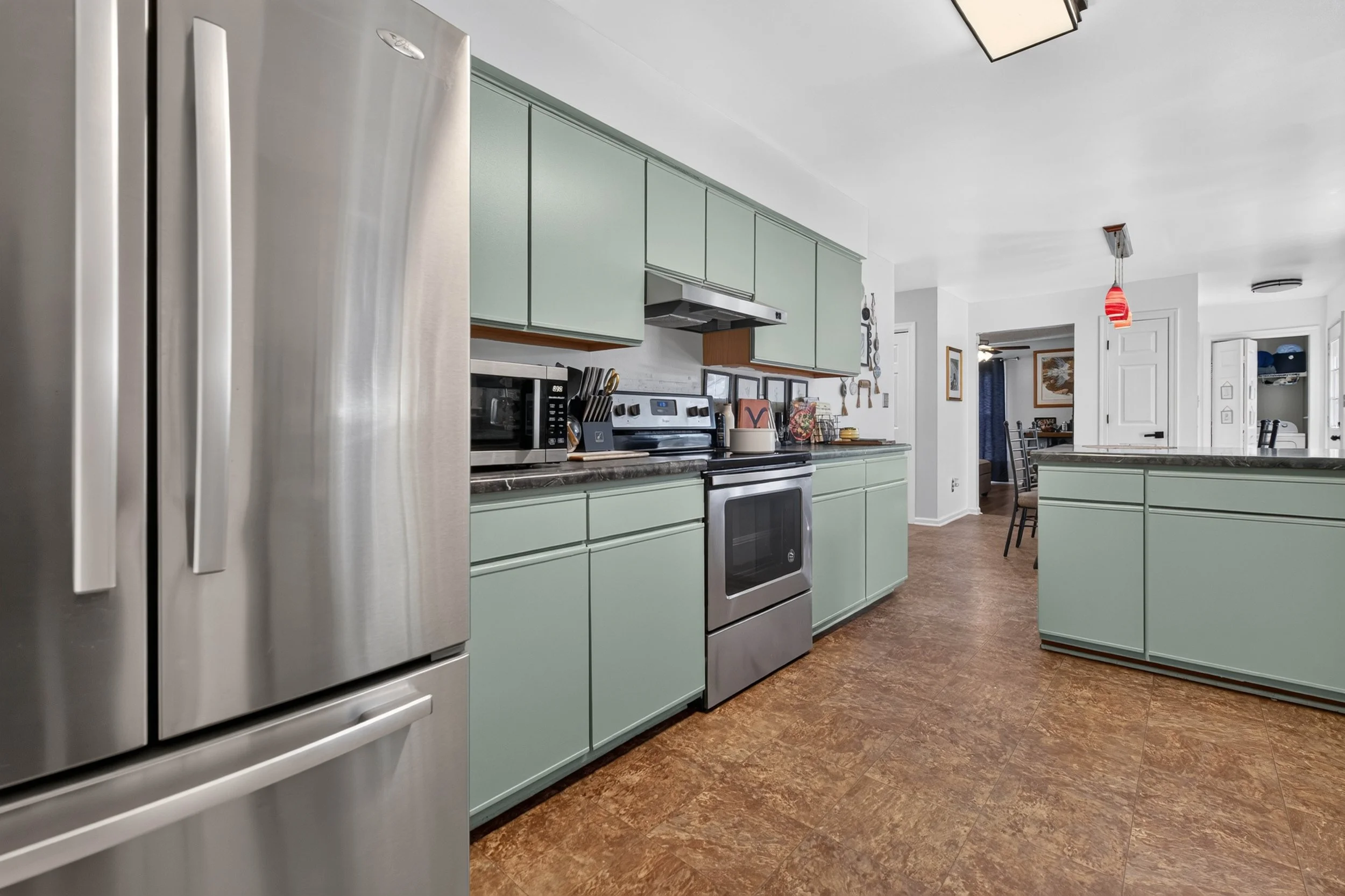 Stainless appliances line one side of the kitchen, with a clear path into the dining area.