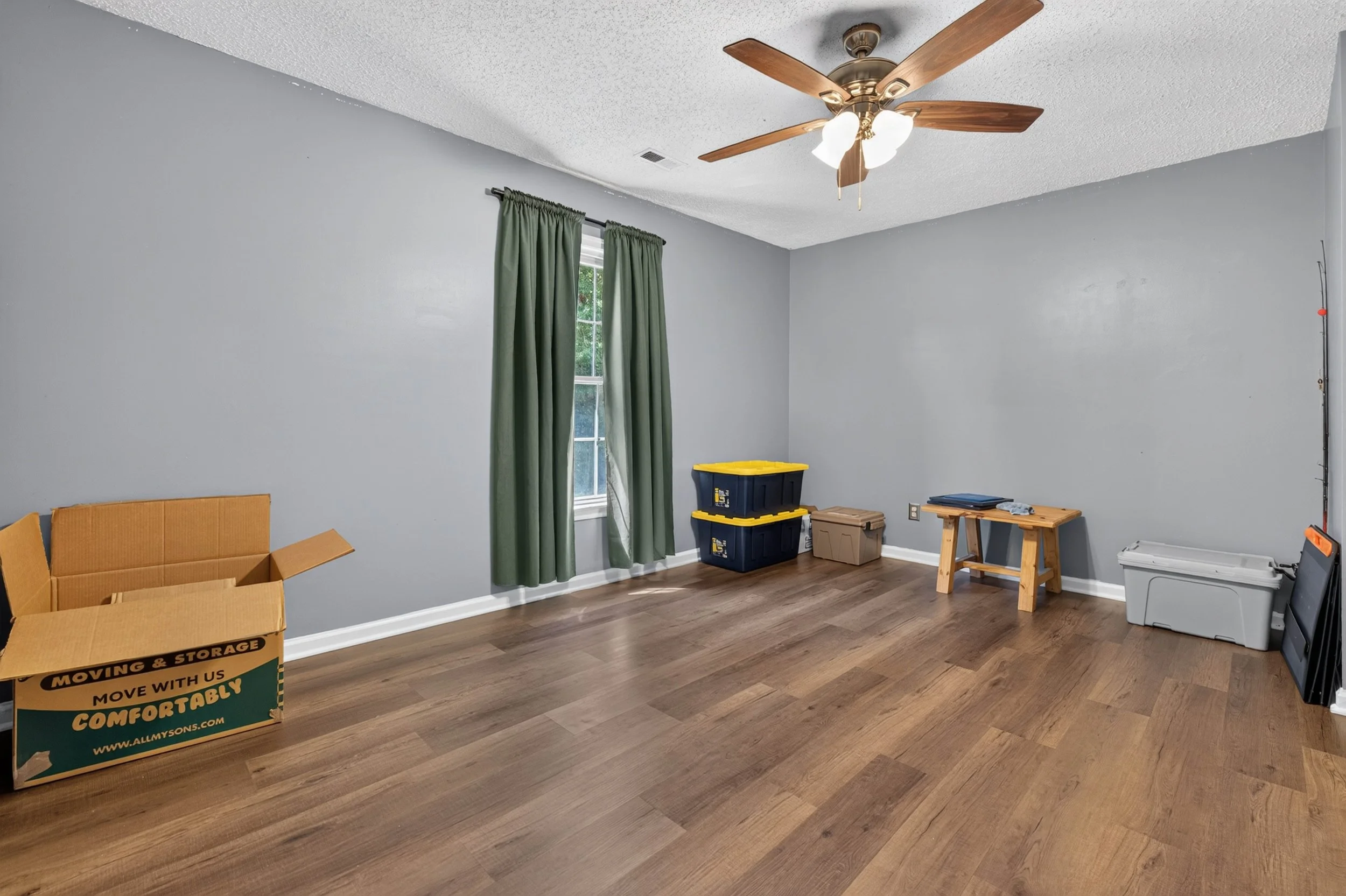 A second upstairs bedroom has an open layout, hardwood-style flooring and a ceiling fan.