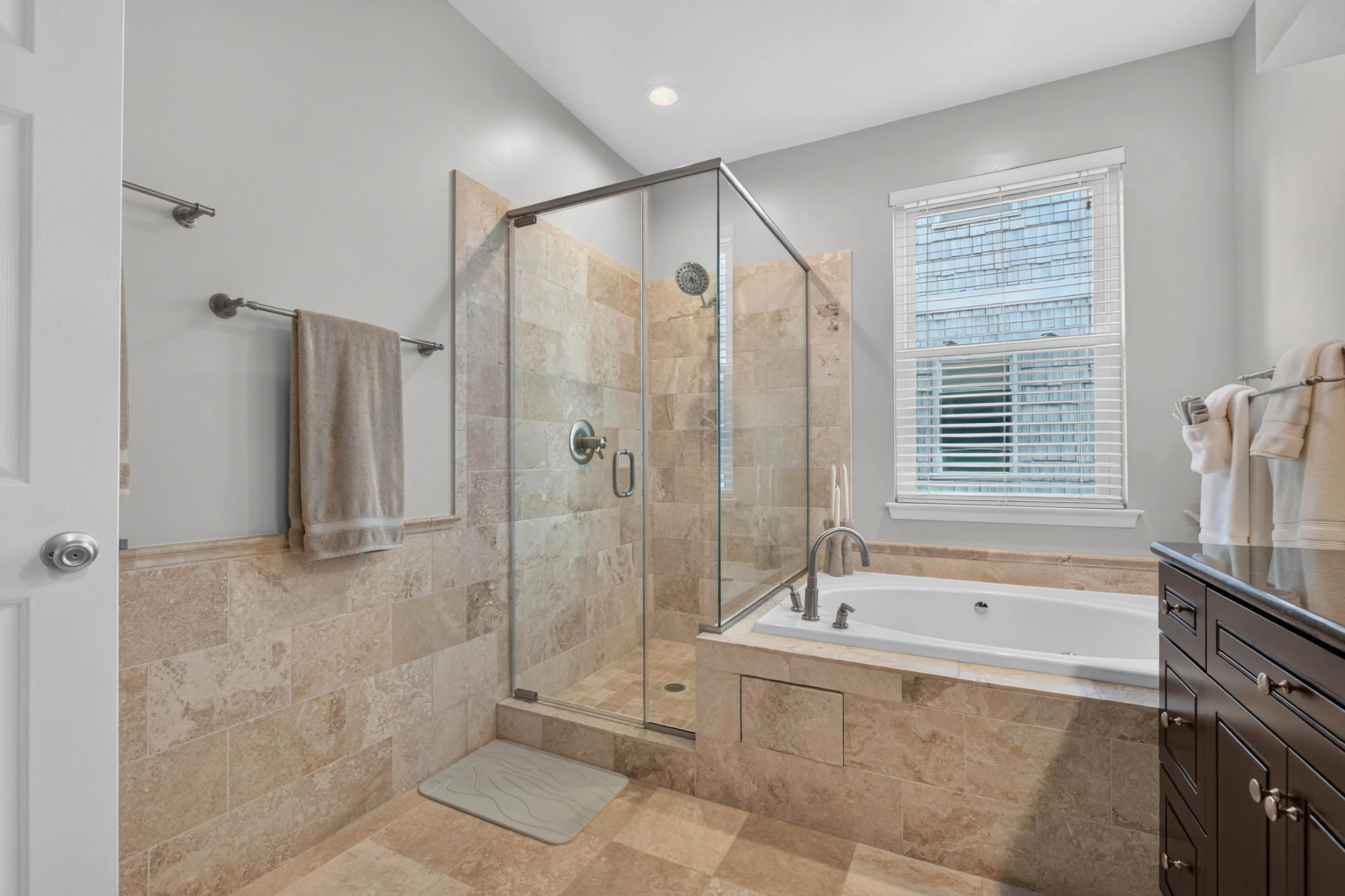 The renovated primary bath offers a glass-enclosed shower and jetted tub, giving every day more than one way to begin or unwind.
