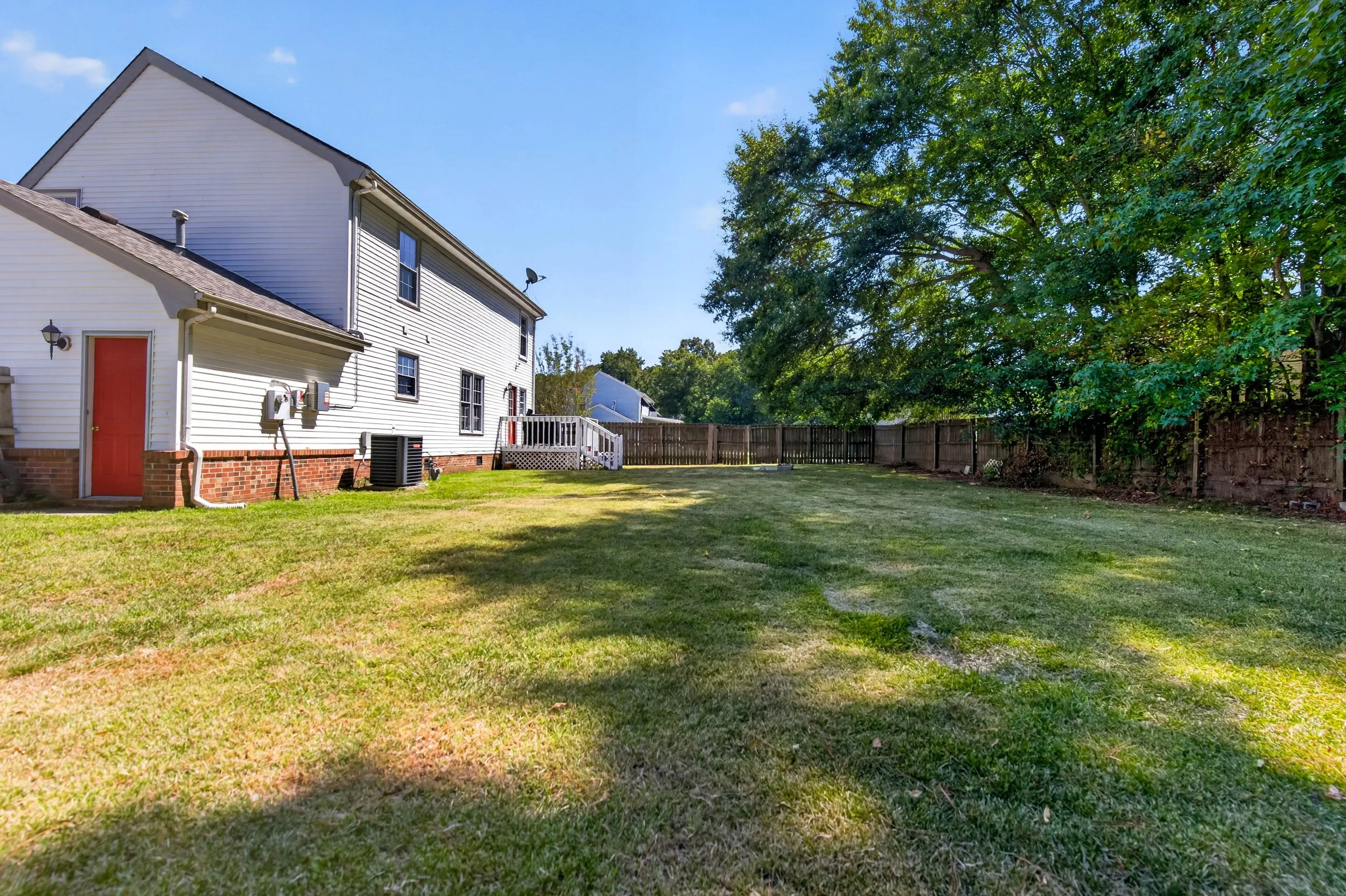 This wide view shows the depth of the fenced backyard behind the home.