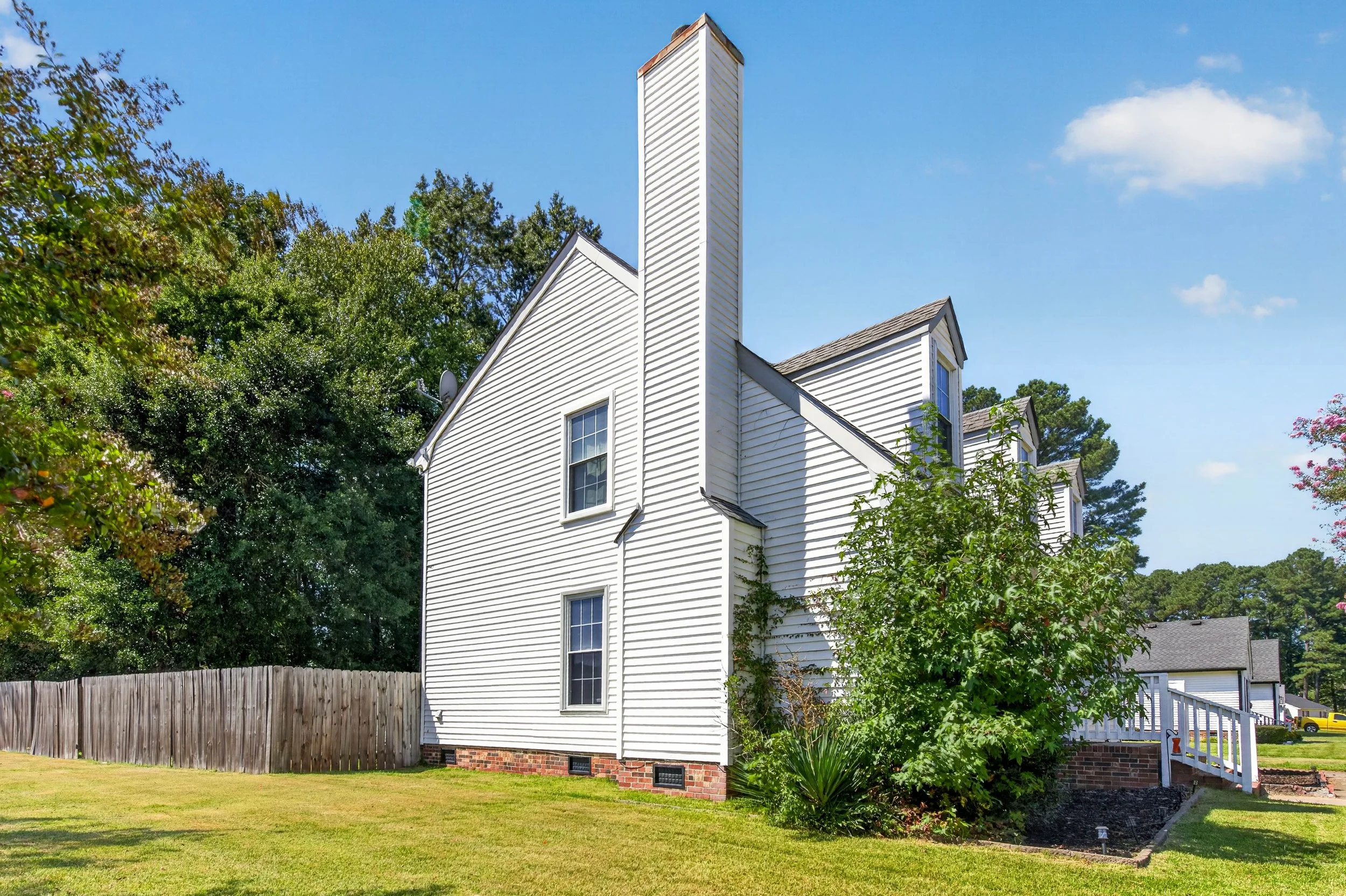 The rear exterior shows the home’s two-story layout, deck and fenced yard.