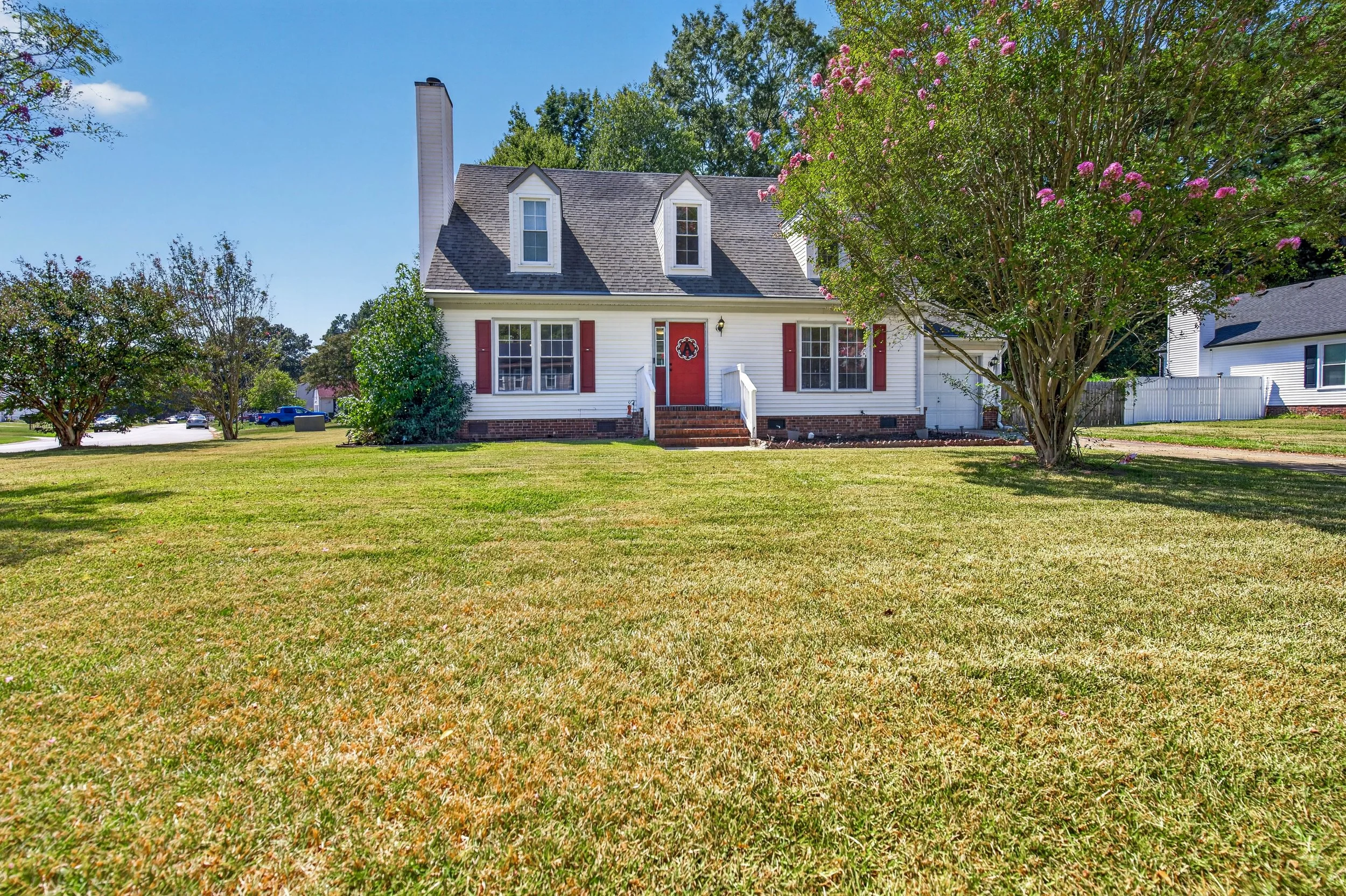 A wide front view shows the home’s traditional exterior and broad corner-lot lawn.