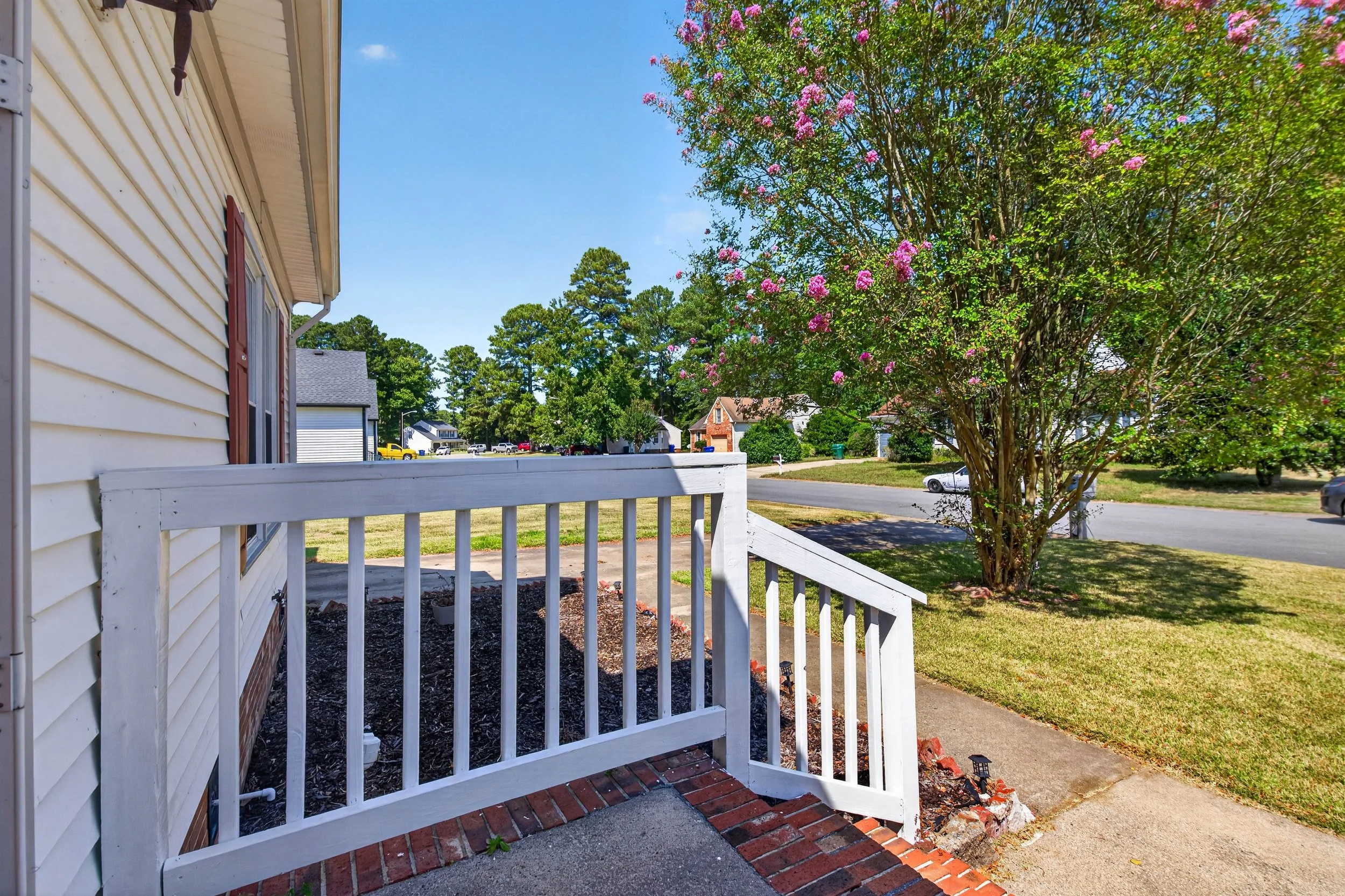 The view from the front entry looks across the corner-lot lawn toward the surrounding Suffolk neighborhood.