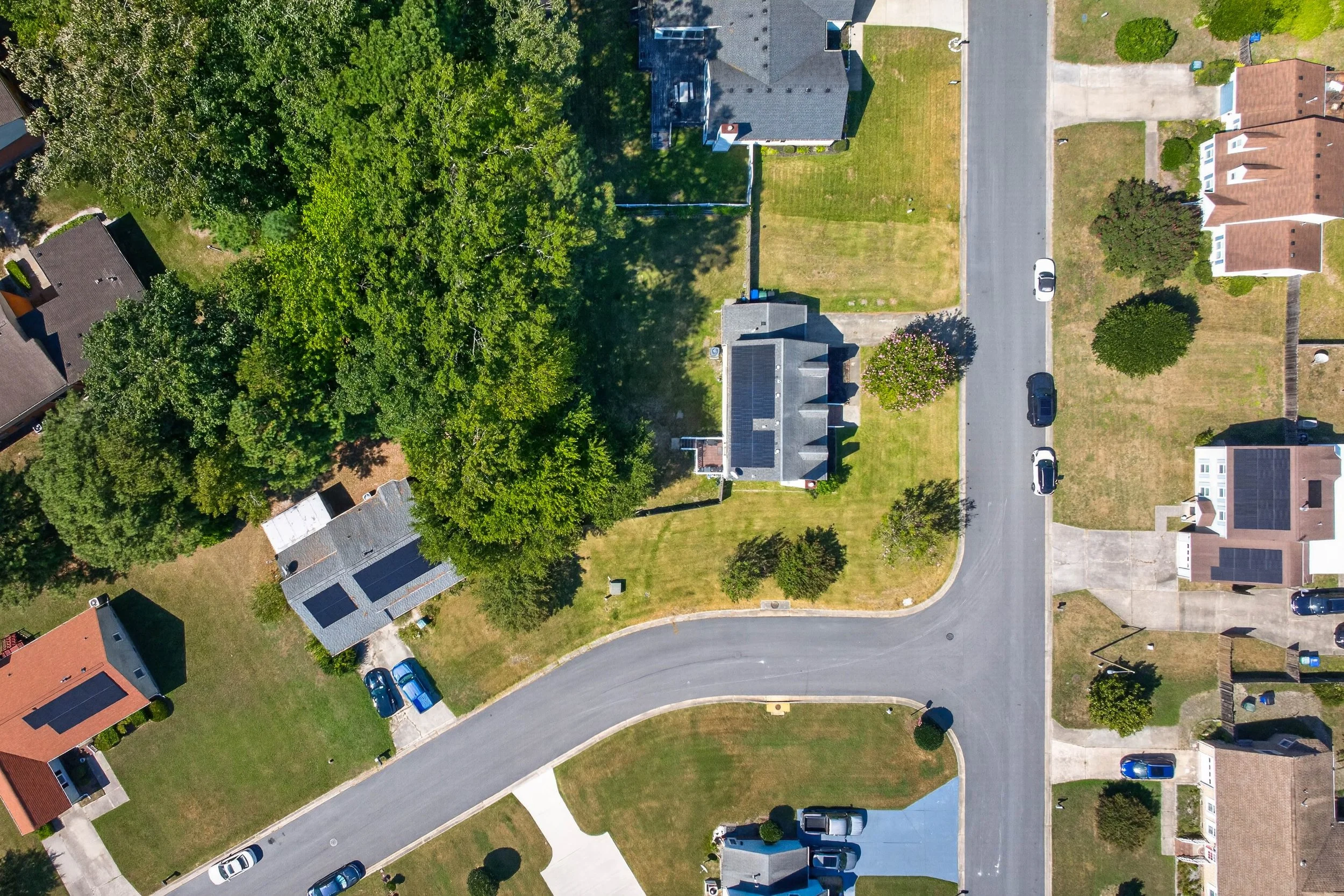 The overhead view shows the corner lot, driveway, fenced backyard and surrounding homes.