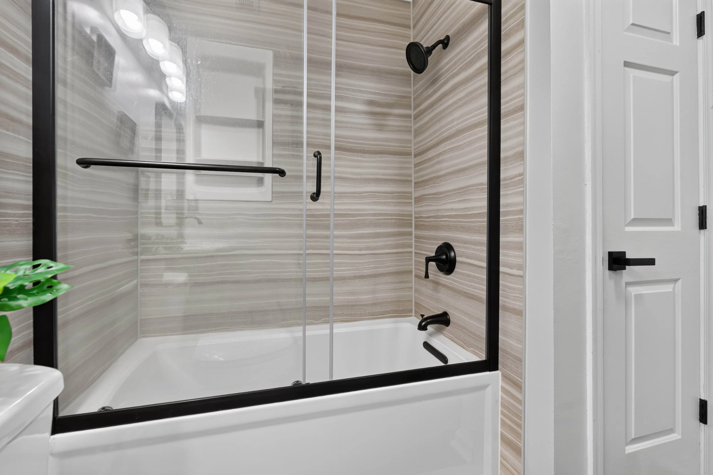 The upstairs bathroom has a glass-enclosed tub and shower with neutral tile.