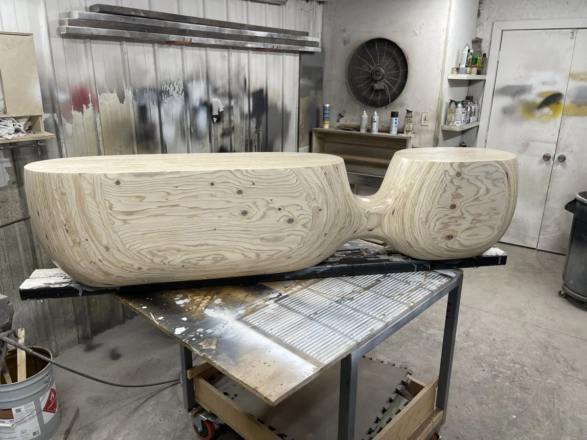 A hand-carved plywood bench going the finish steps