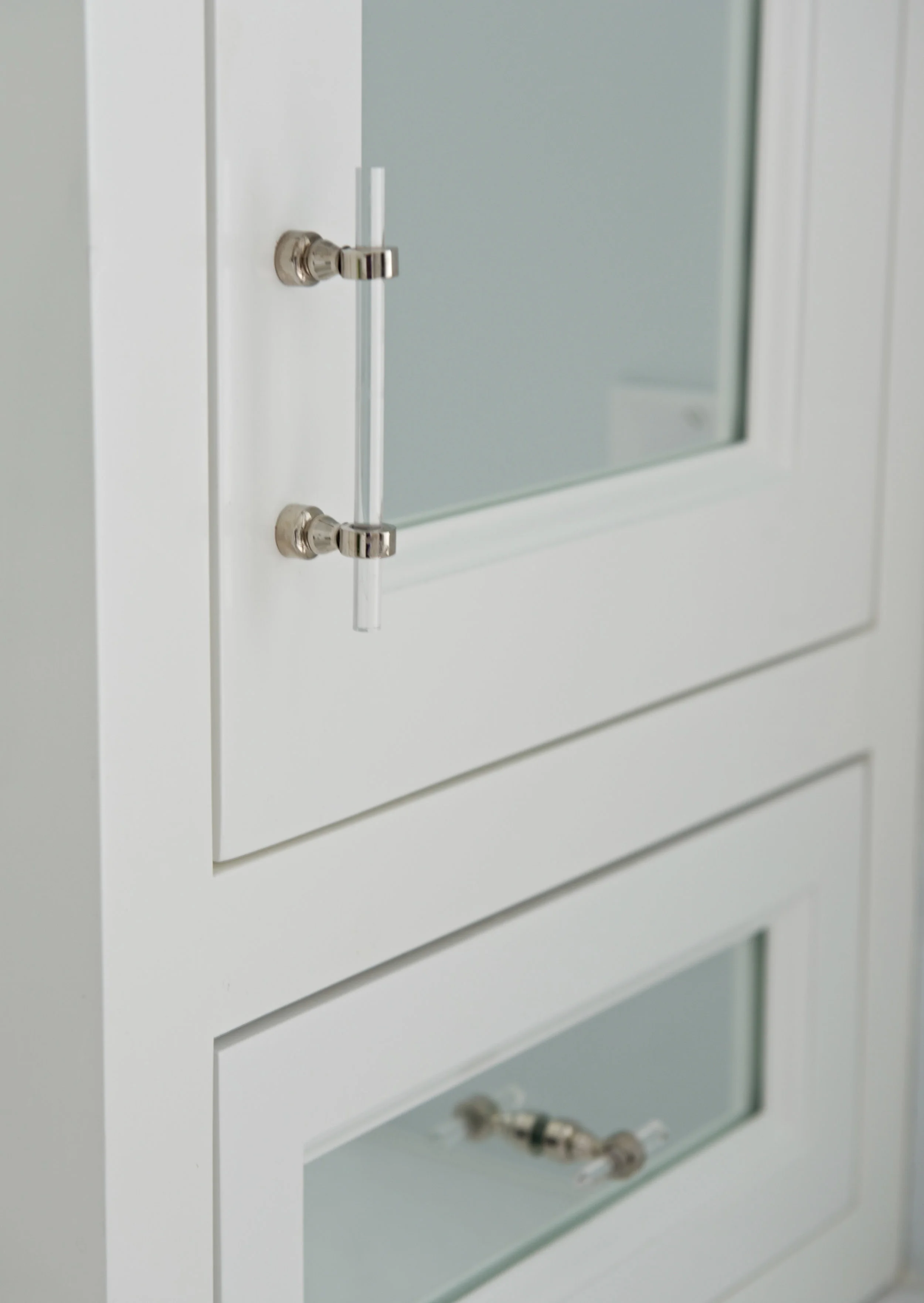 Bathroom Cabinetry with mirrored insets and glass hardware