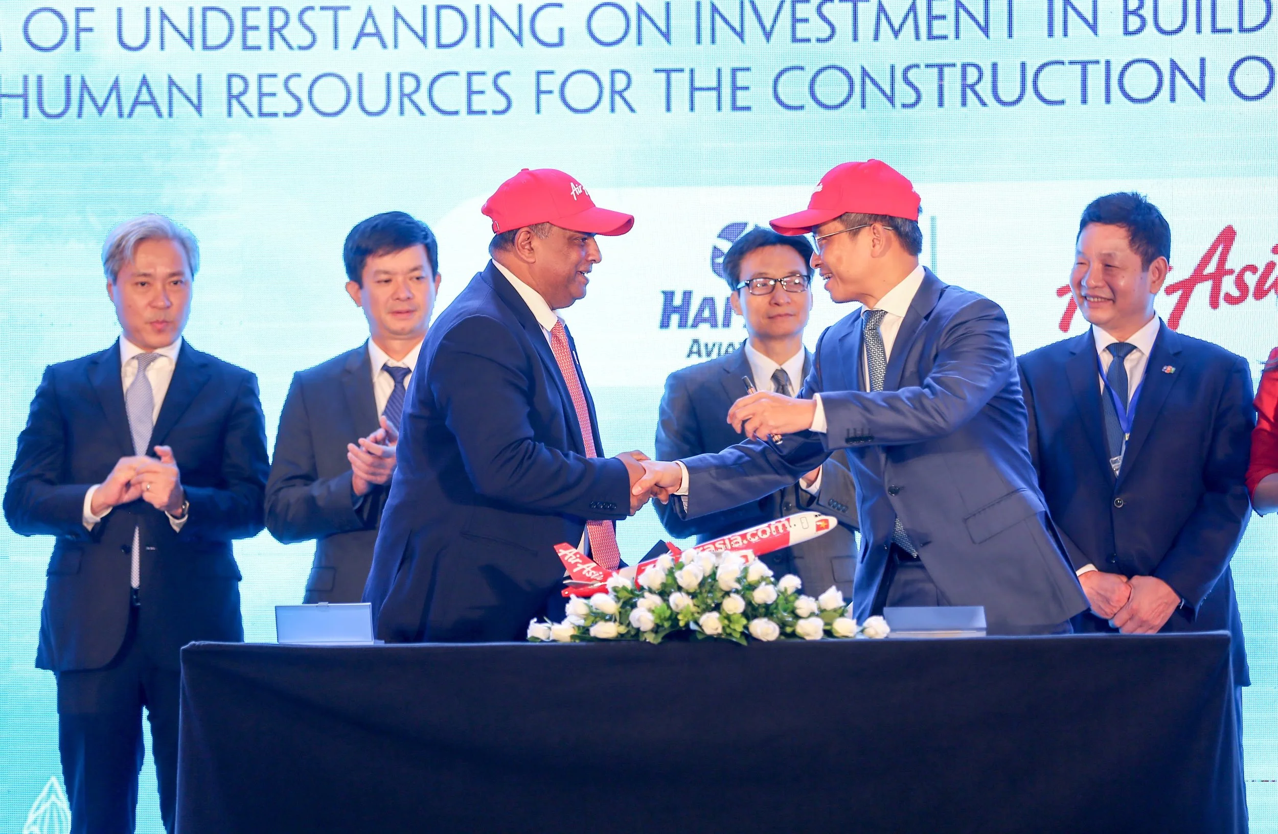 Giám đốc điều hành Tập đoàn AirAsia Tony Fernandes (phía trước bên trái) bắt tay với Chủ tịch HĐQT Công ty Cổ phần Du lịch Thiên Minh và Công ty Cổ phần Hàng không Hải Âu Trần Trọng Kiên sau khi ký biên bản ghi nhớ dưới sự chứng kiến của Phó Thủ tướng Việt Nam Vũ Đức Đam (giữa bên phải) và Thứ trưởng Bộ Văn hóa, Thể thao và Du lịch Lê Quang Tùng (giữa bên trái), cùng với Trưởng ban Nghiên cứu Phát triển Kinh tế tư nhân (Ban IV) Trương Gia Bình (ngoài cùng bên phải) và Don Lam Phó trưởng Ban IV (ngoài cùng bên trái).