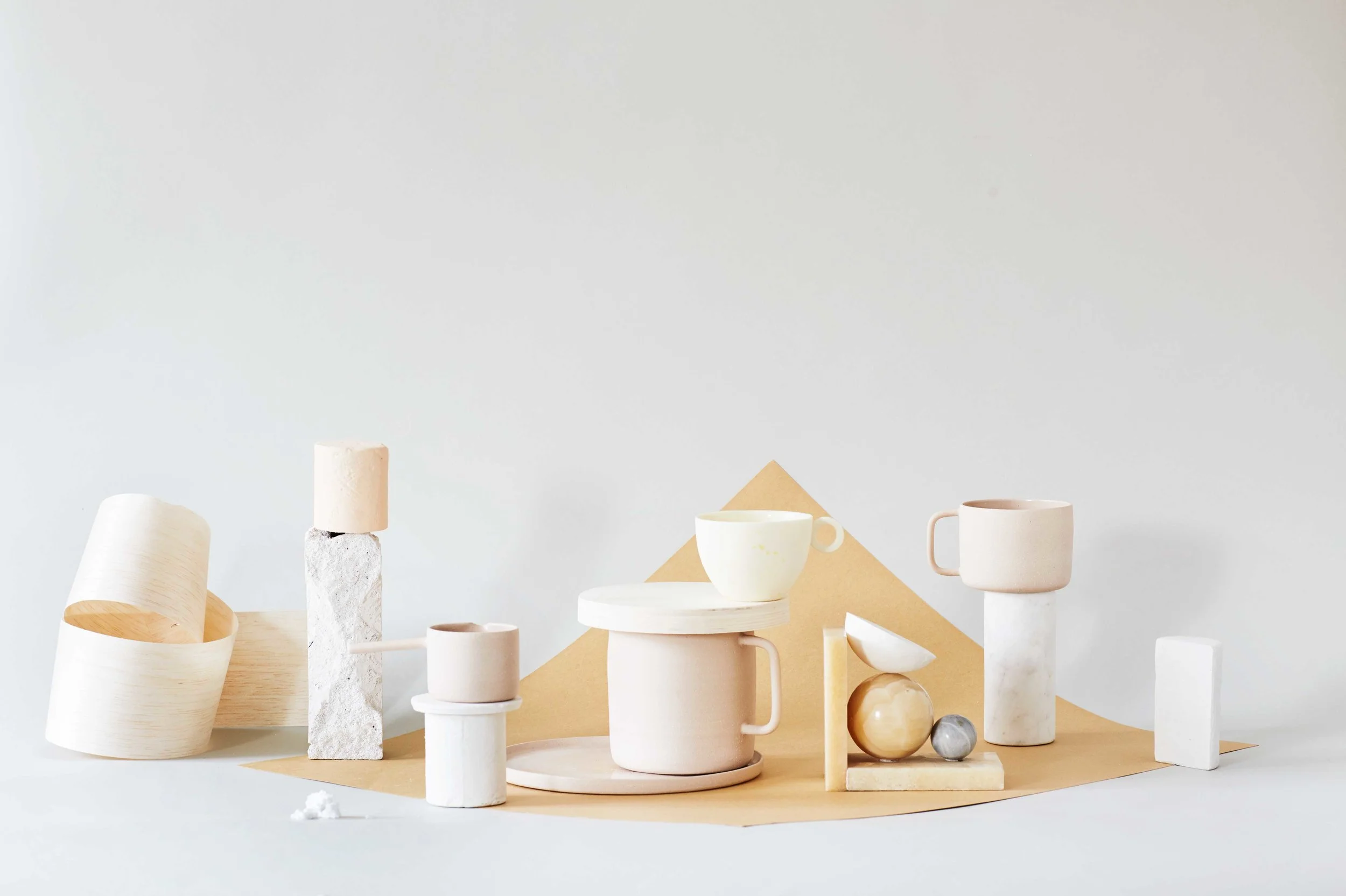 //beige Wood cylinder private / sculpture plaster by Appeal Magazine / Cylinders plaster, different sizes all from Appeal Magazine / Ghost pourer Yonobi Studio / Cup Yonobi Studio/ Hasami porcelain mug Yonobi Studio / Bookend marble Padmo & Vig / Damhus mug Yonobi Studio