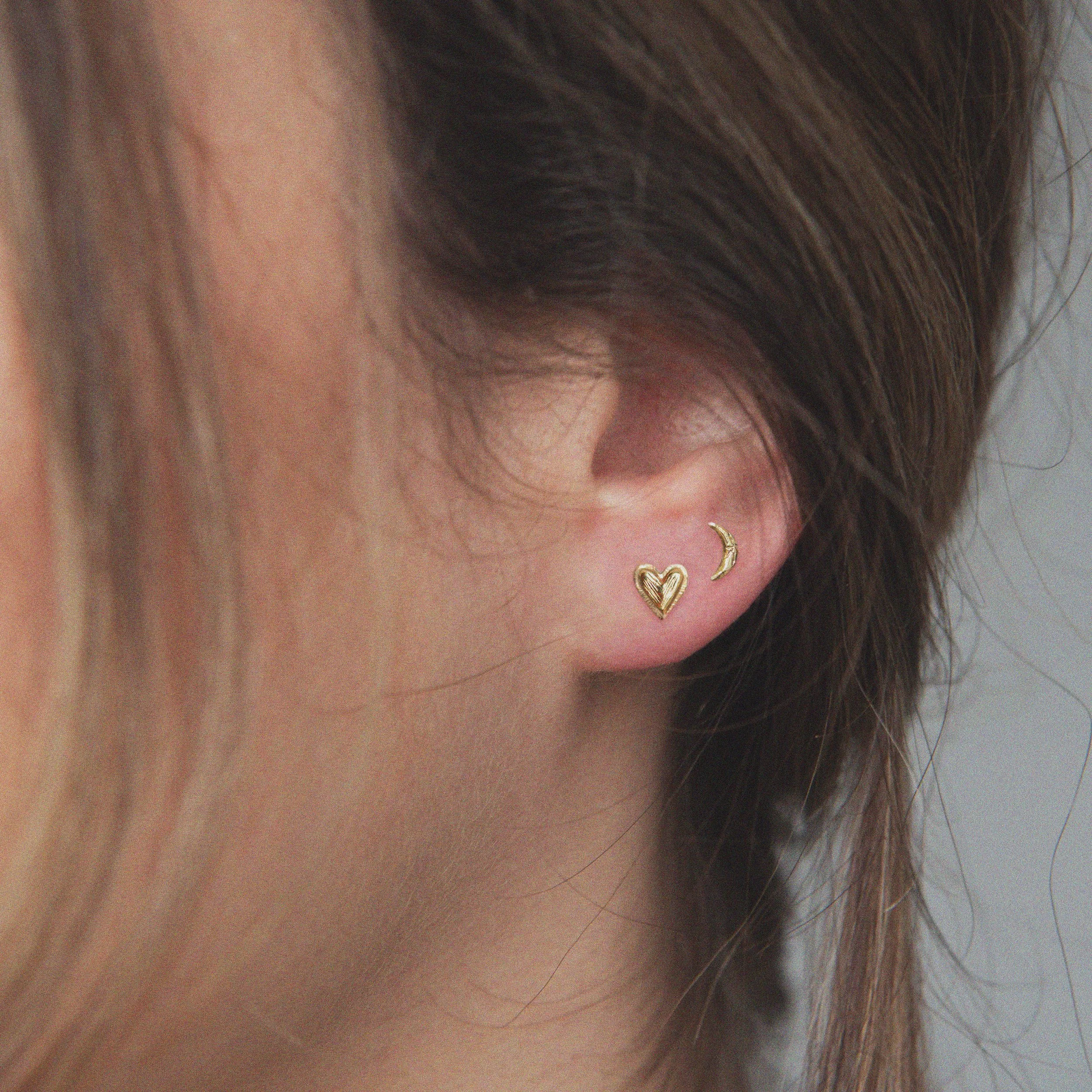 little heart and crescent moon gold earrings shown on a model