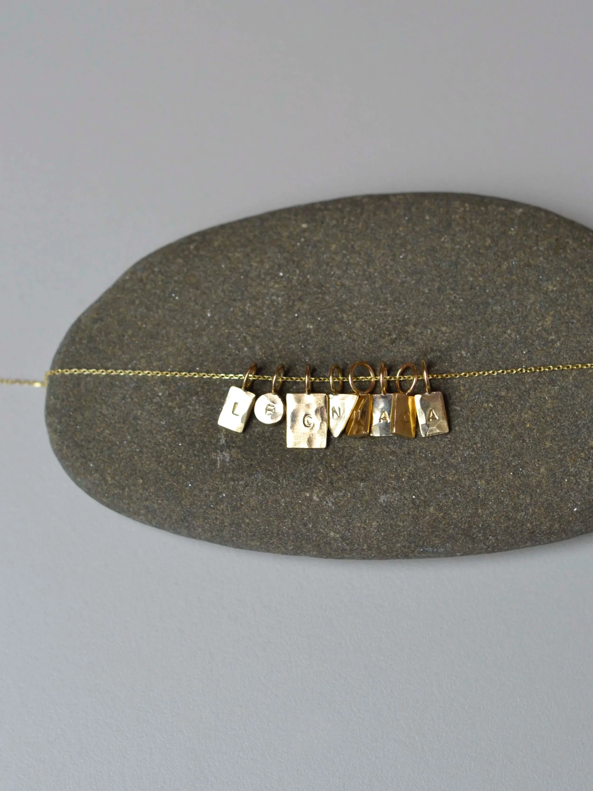 Gold necklace displayed on a gray, textured oval-shaped background.