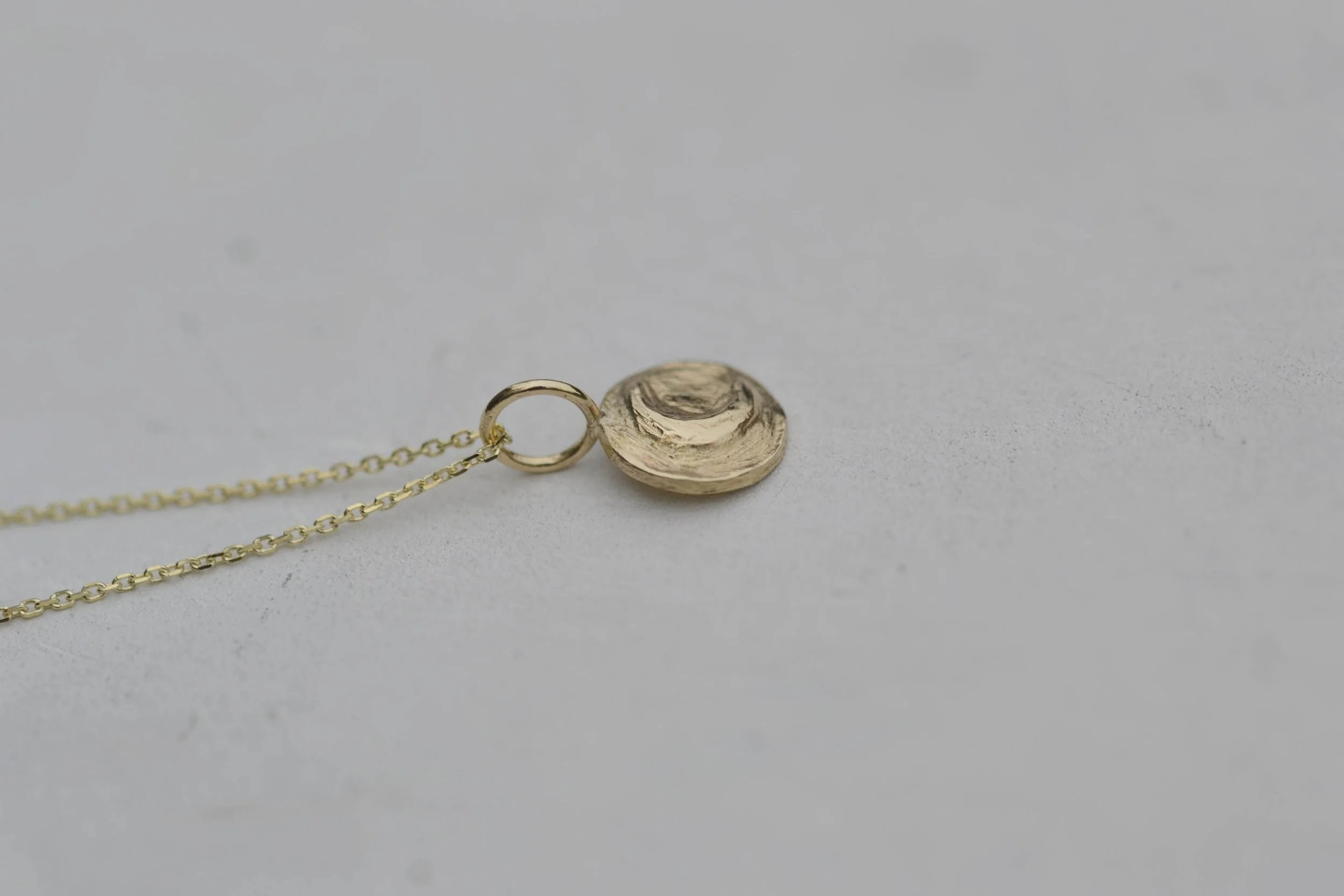 side view of gold celestial coin pendant on a chain