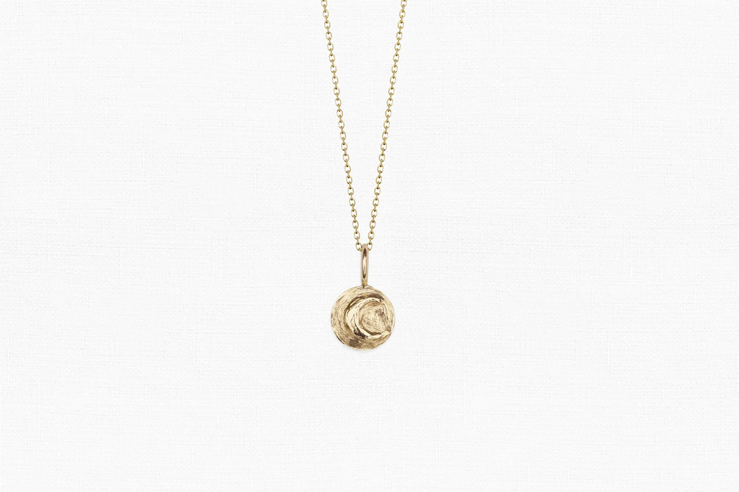 Solid gold crescent moon necklace on delicate chain and white background