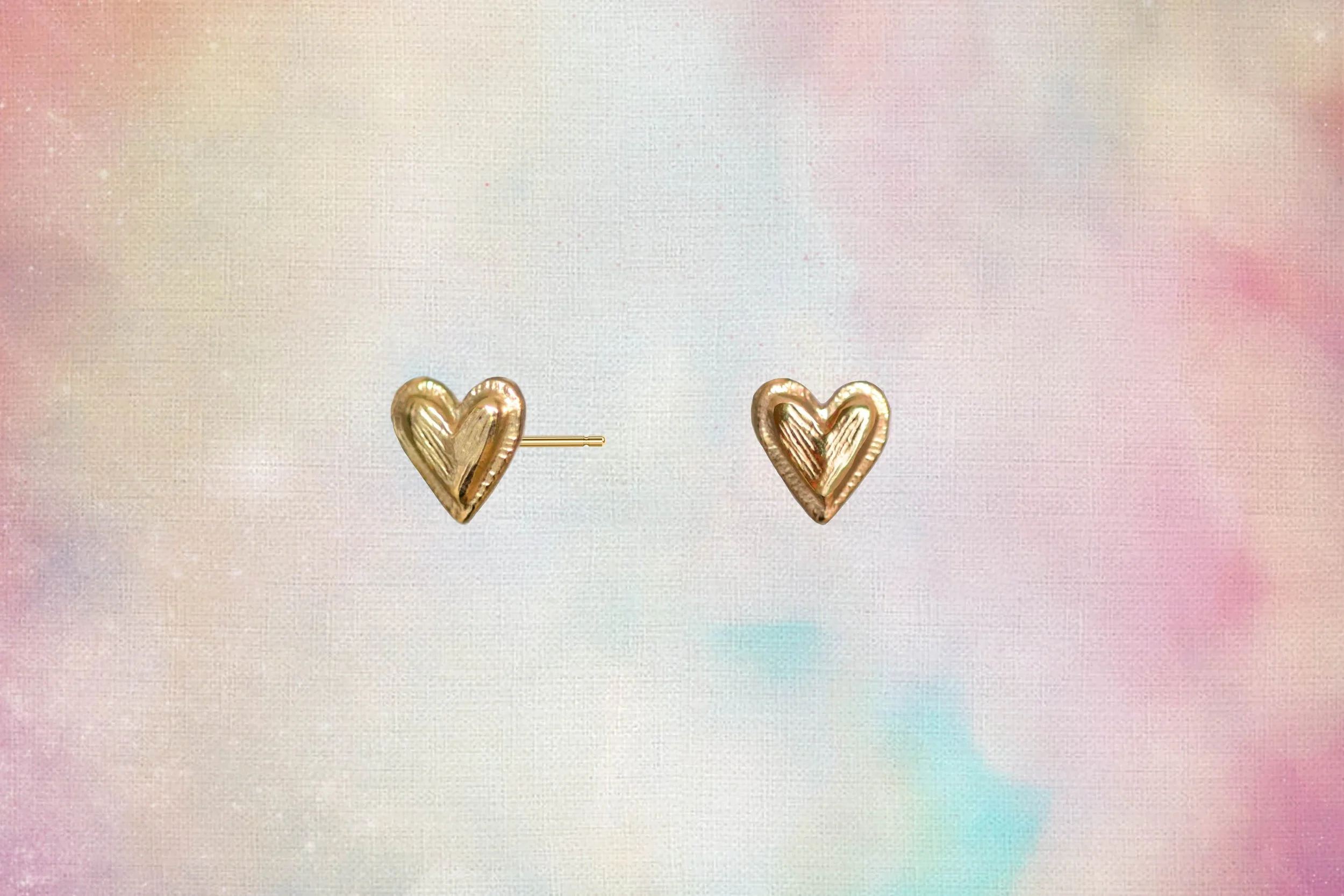 textured gold heart stud earrings on multicoloured background