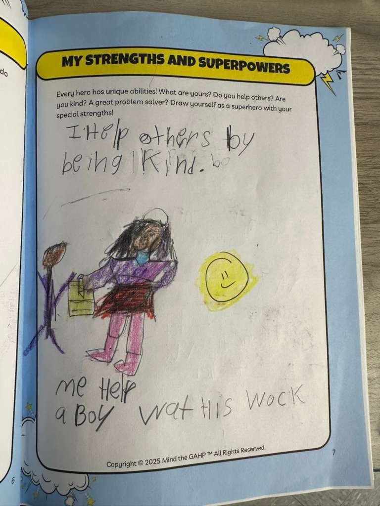 Child's drawing of a girl helping a boy with his work, depicted with colorful crayon, accompanied by a yellow smiley face, in a classroom activity worksheet titled 'My Strengths and Superpowers'. The child wrote 'I help others by being kind' and 'me 