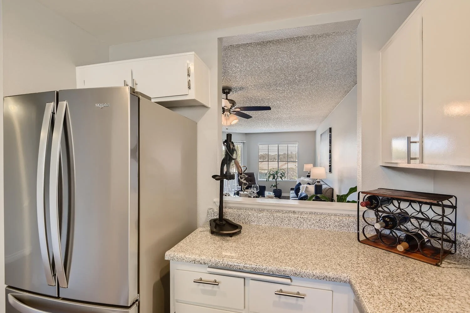 The Kitchen area with a 3 door stainless steel fridge with large counter space and a window looking into the living area
