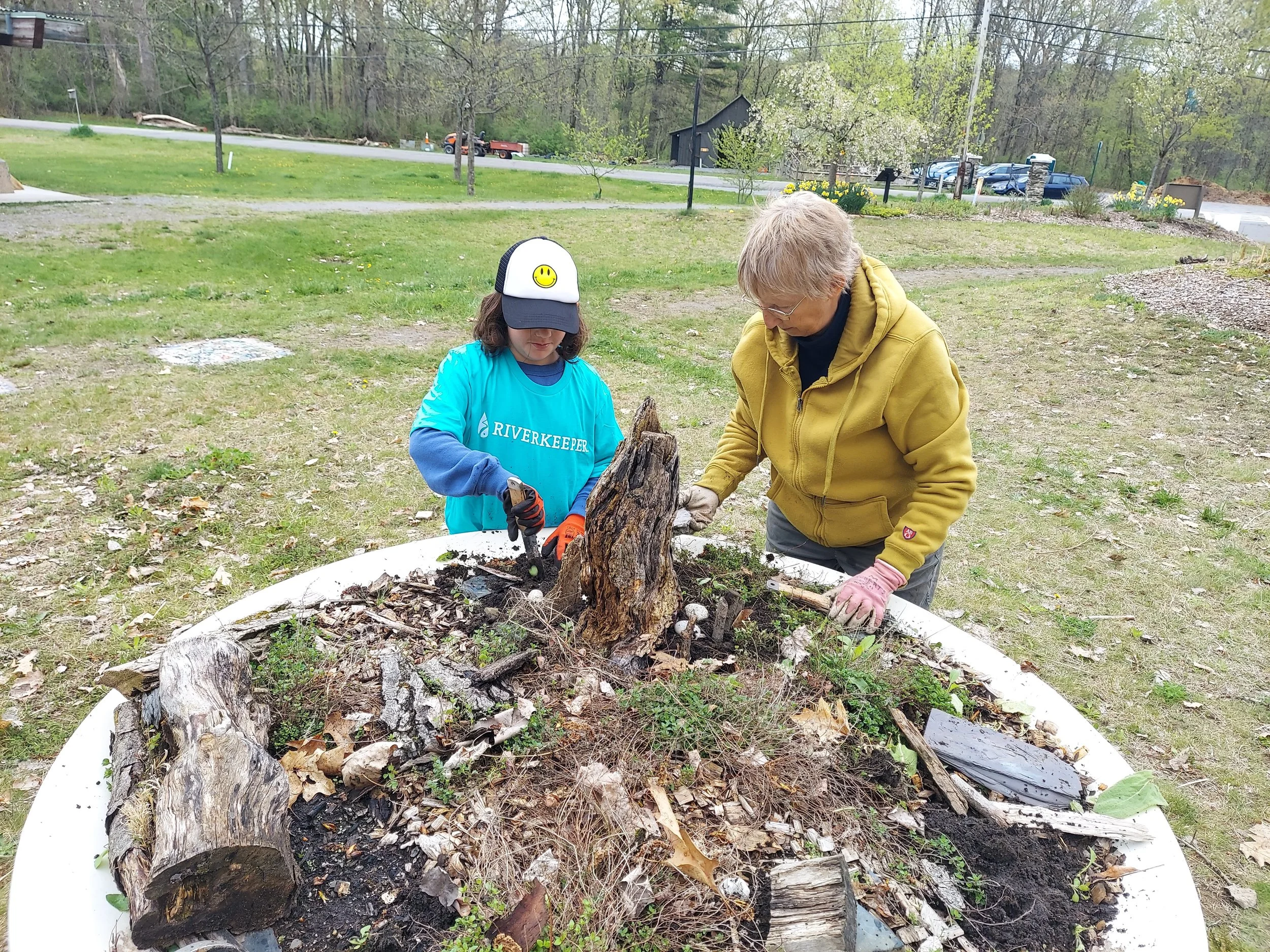 Two volunteers help to clean up a raised garden bed.