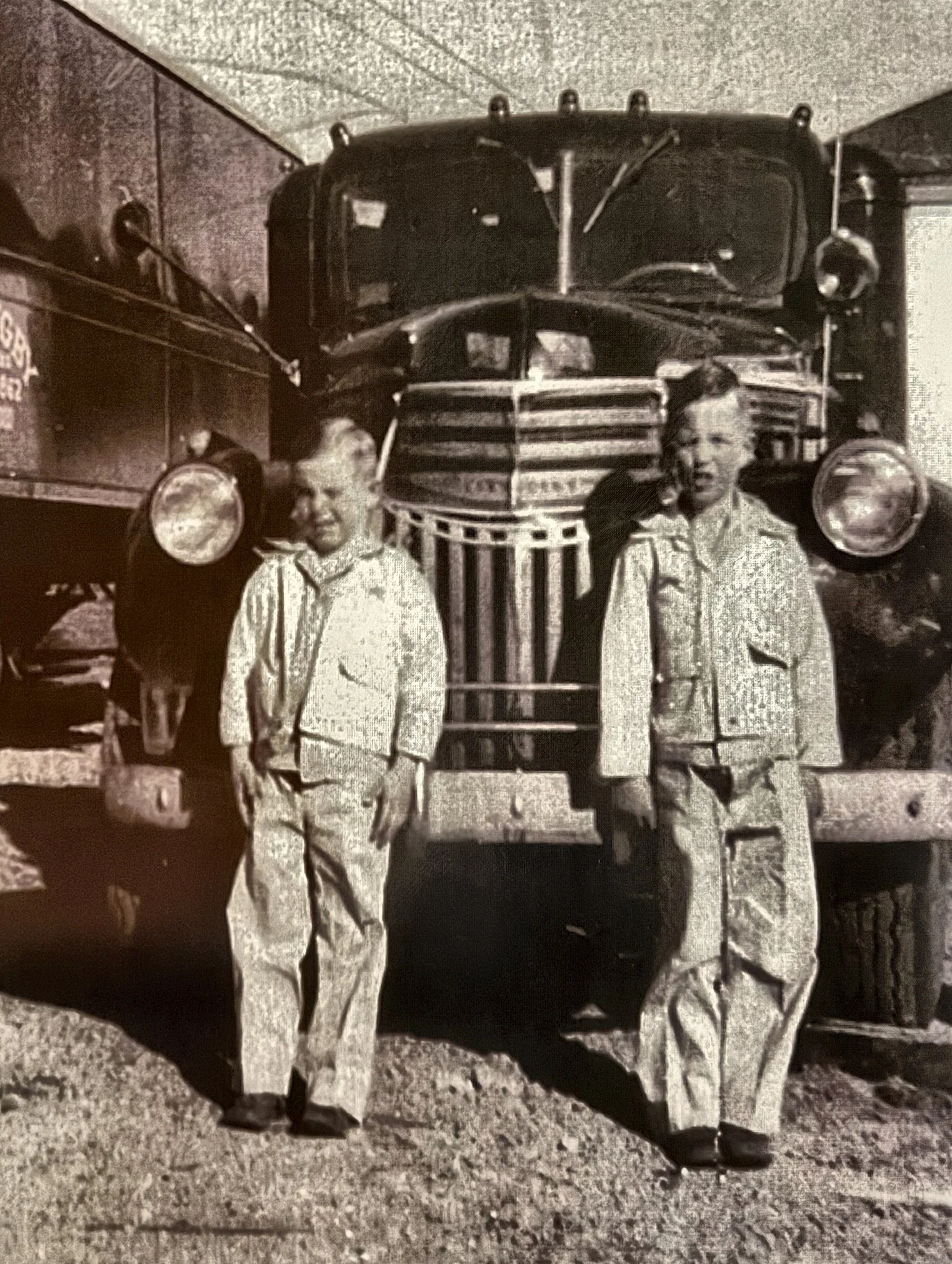 Two boys in matching outfits standing in front of an early Digby truck