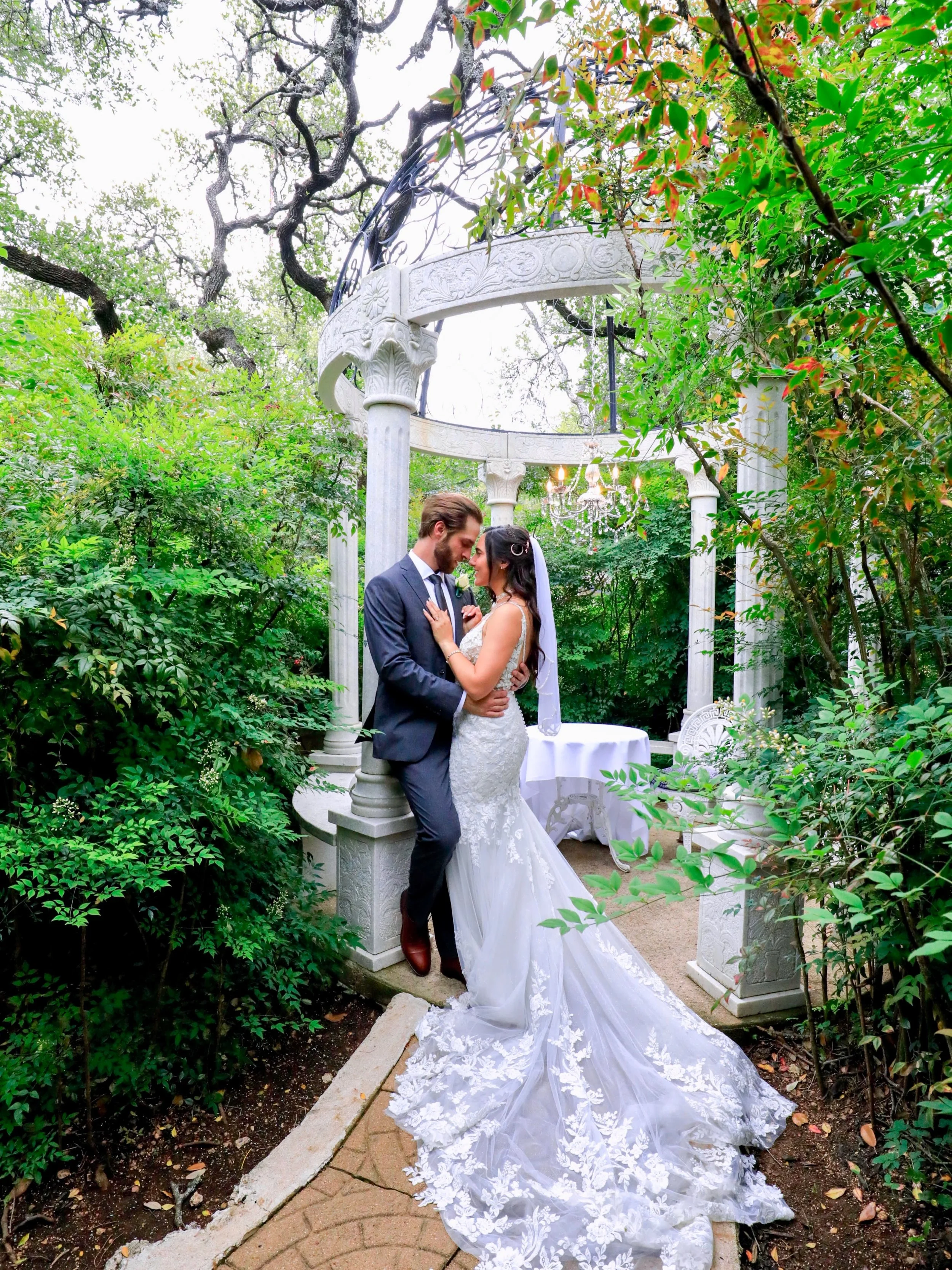 The couple embraced a timeless editorial pose, standing effortlessly close as they gazed into the distance with quiet confidence. Their posture was elegant yet natural, creating a refined balance of romance and sophistication. Framed by beautiful lig