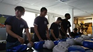 Michael, Akeem, Justin, and Mohammed practice CPR on infant manikins