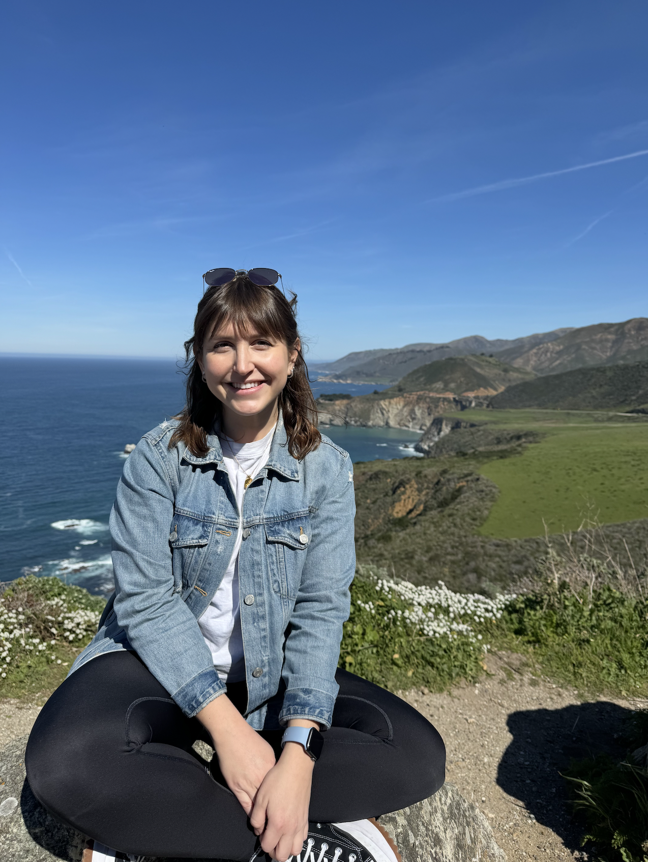 A photo of Paulina sitting on a large rock that overlooks the coast in Big Sur California