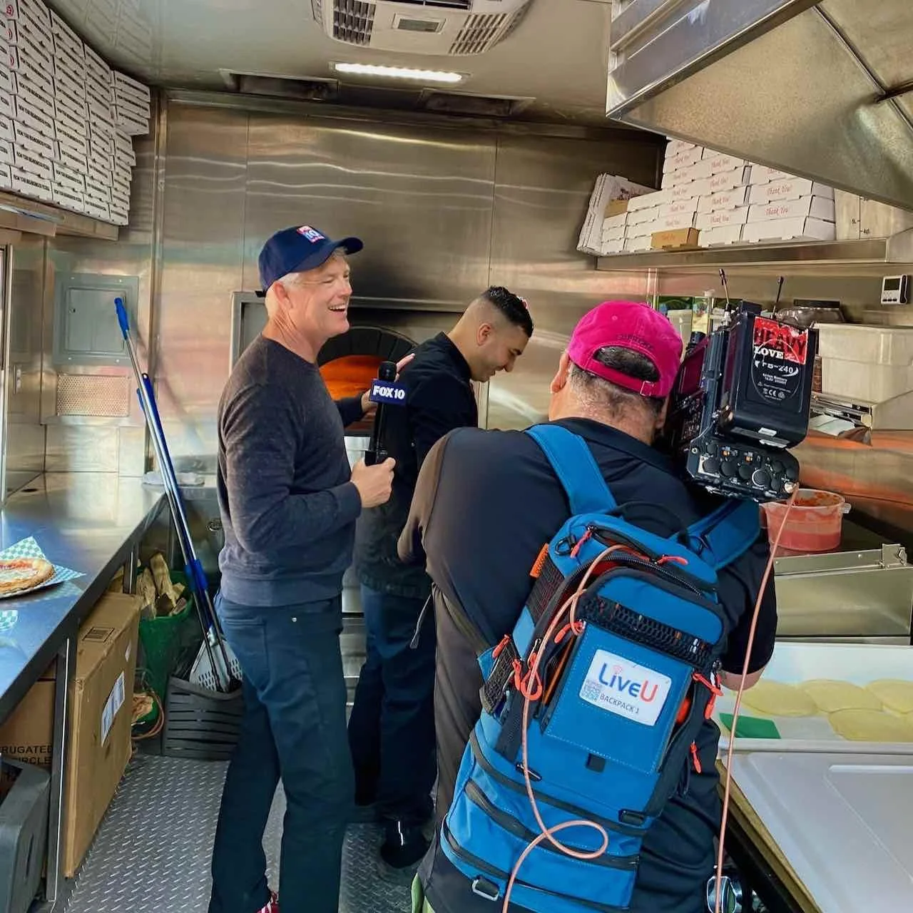 Cory McCloskey of FOX 10 Phoenix covering Re Di Roma Wood-Fired Pizza as Oualid Ferhati makes pizza by the wood-fired oven.