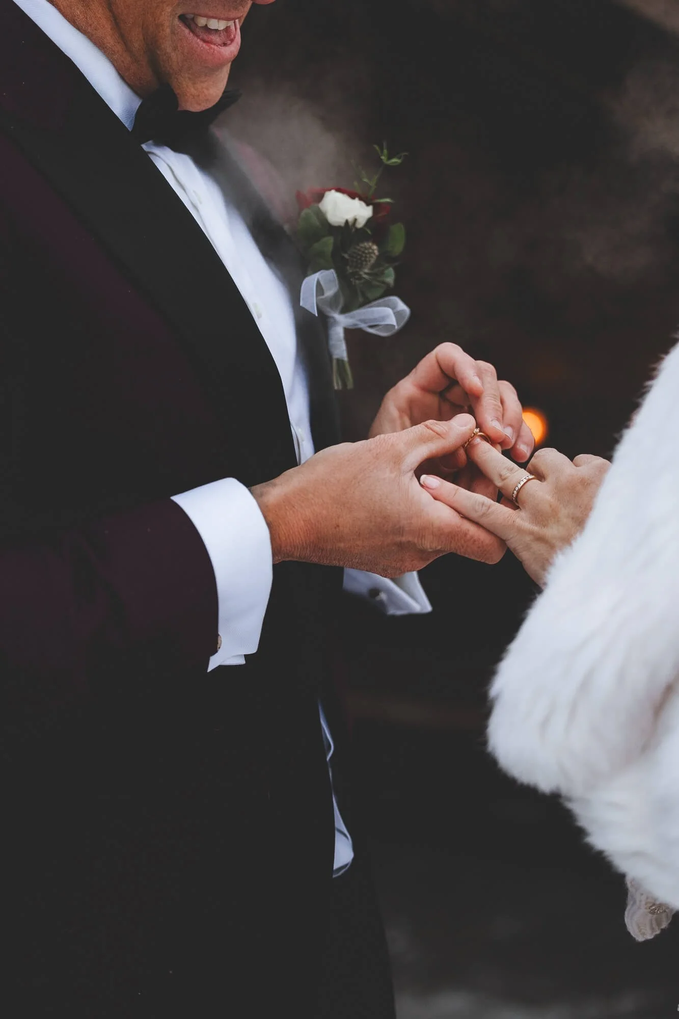 Close-up of a groom in a tuxedo exchanging wedding rings with a bride, with the bride's hand visible. Wedding photographer in Lapland, Finland. 