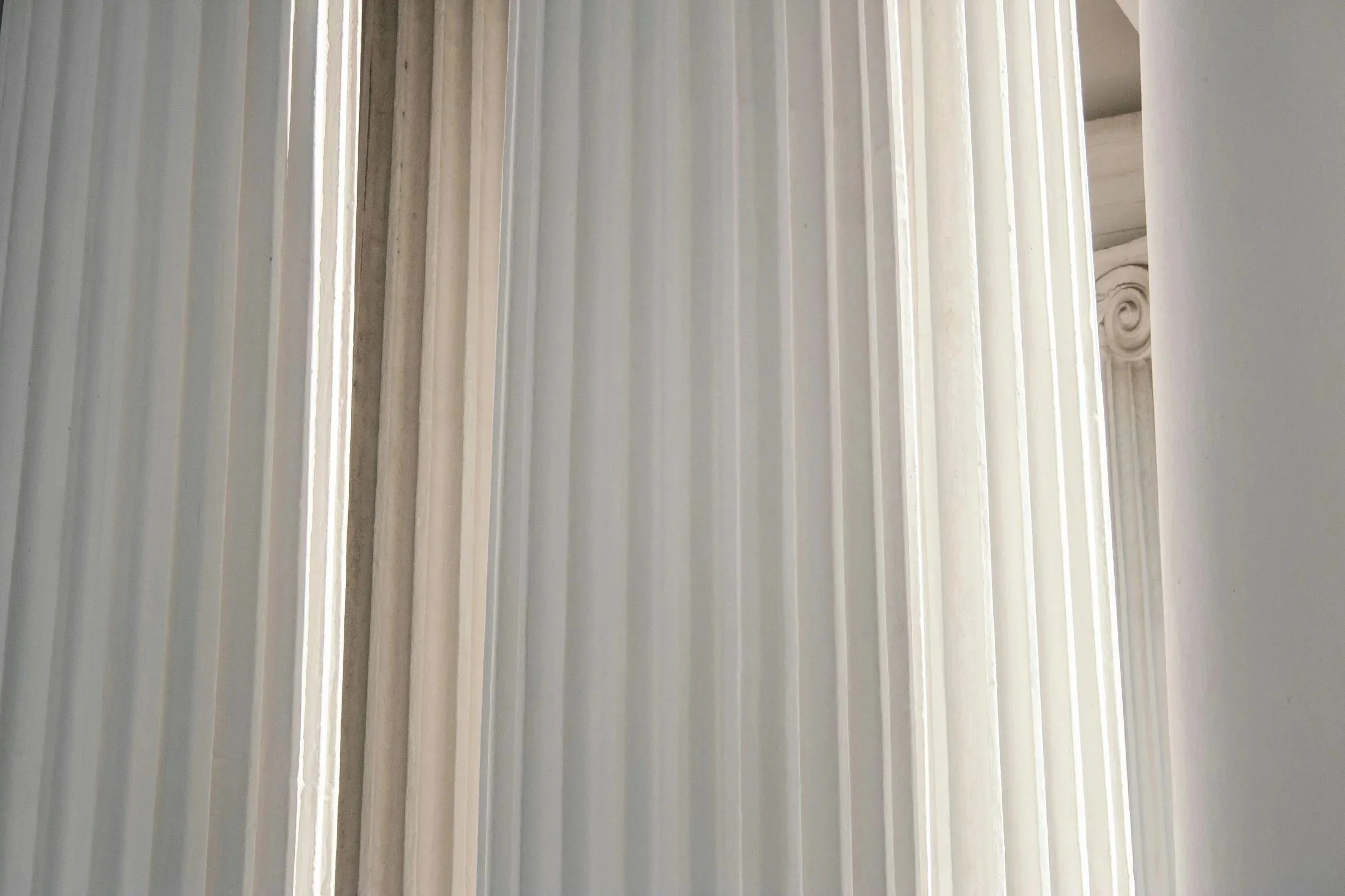 Close-up of a white, fluted column with ornate details, part of a classical architectural structure.