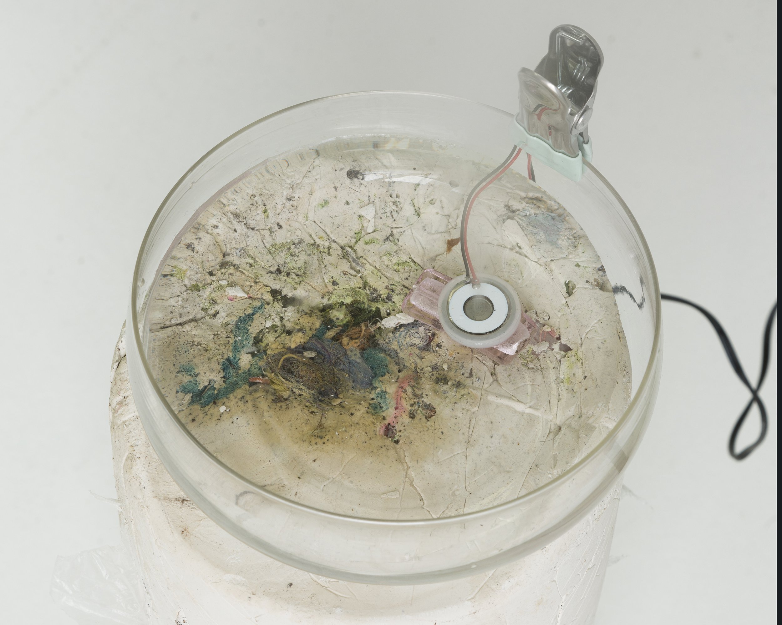   Fog House  (detail) ,  2022. Plaster, compost soil, glass pendent, clip, atomization sensor, studio debris. 21.5 x 6 x 6 inches. 