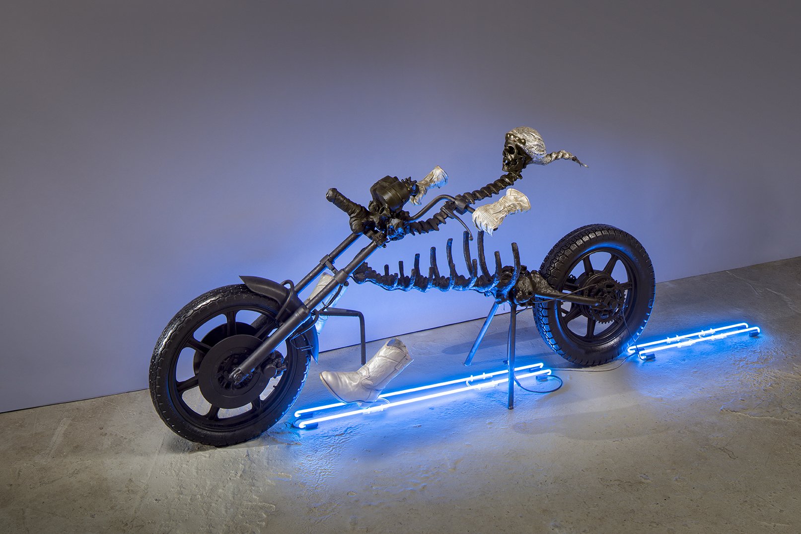  Marsha Pels,  Dead Cowboy , 2007-2008. Cast epoxy resin, cast rubber, deconstructed motorcycle, steel, neon lights, argon- mercury text on wall. 48 x 120.5 x 36 inches. 