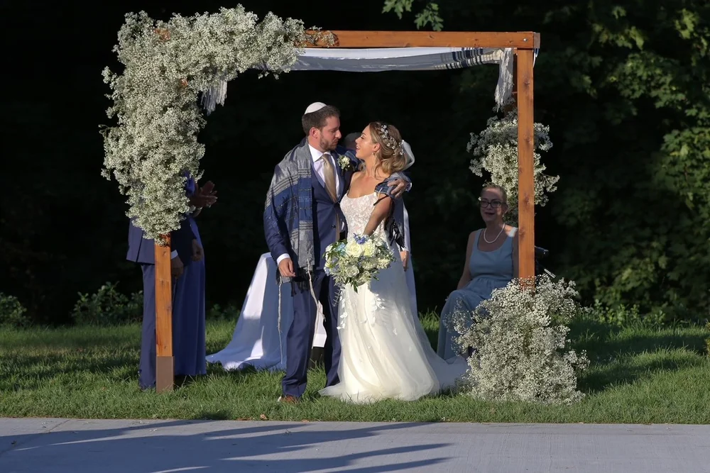 Couple under a floral wedding arch at their ceremony