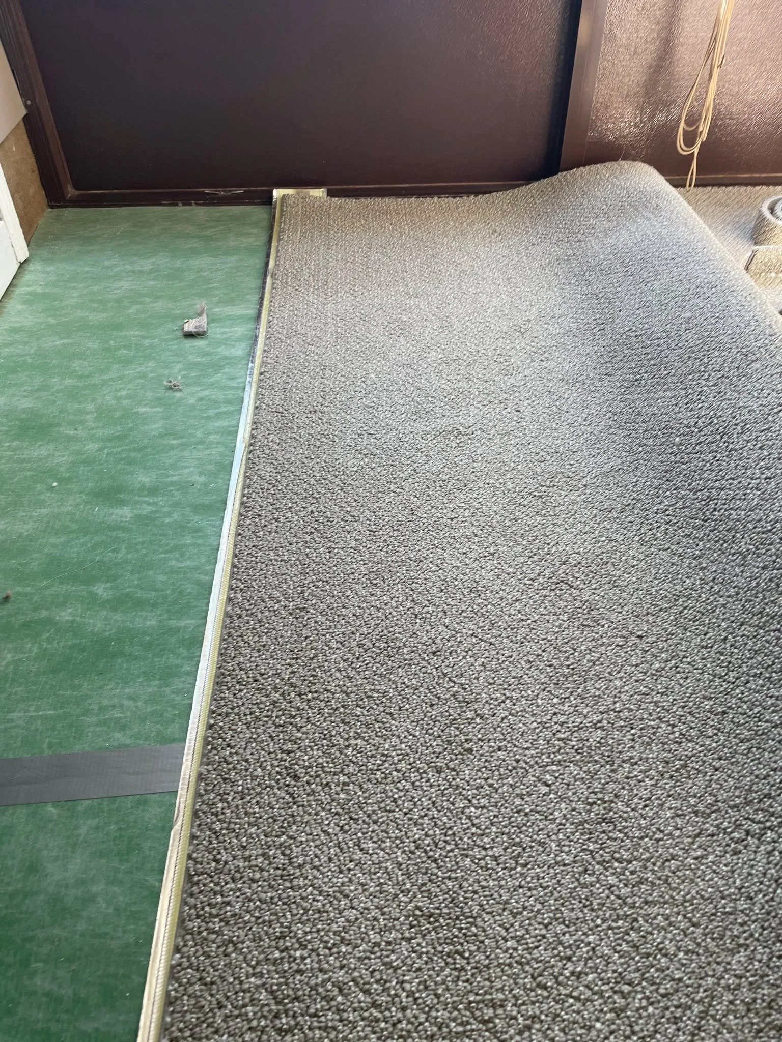 We removed the loose layers of carpet and pad while keeping the glue direct intact to provide extra cushion and insulation. The carpet base around the slider door was replaced, and the Berber was carefully sealed and fitted to follow the contours of