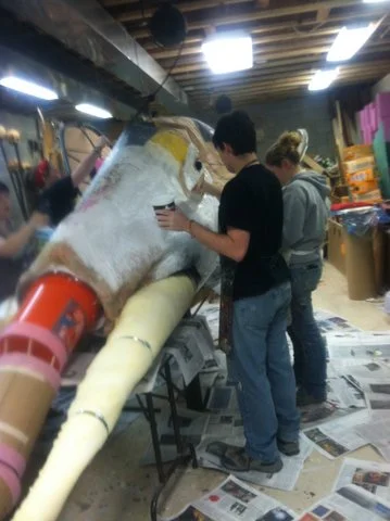 STEAMPUNK MAMMOTH  GIANT PUPPET HEAD:  Dream play: works in        progress, final form with         white undercoat: chicken wire, wood frame, tubes, buckets, paper and cloth mache, mixed materials