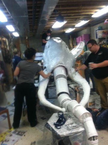 STEAMPUNK MAMMOTH  GIANT PUPPET HEAD:  Dream play: works in        progress, final form with         white undercoat: chicken wire, wood frame, tubes, buckets, paper and cloth mache, mixed materials