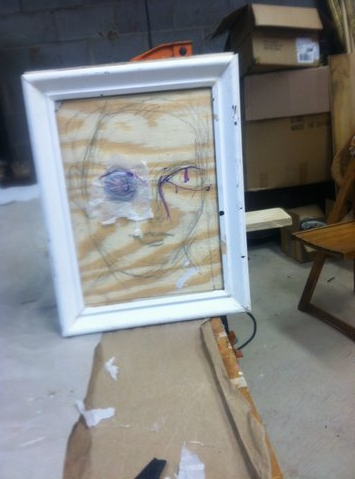 RIGGED PORTRAIT: A Little Night Music: rigged so a knife, supposedly thrown, springs out of the eye; wood, springs, duplicate knife handles, steel wire, pulleys, picture frame