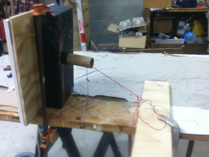 RIGGED PORTRAIT: A Little Night Music: rigged so a knife, supposedly thrown, springs out of the eye; wood, springs, duplicate knife handles, steel wire, pulleys, picture frame