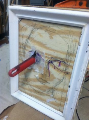 RIGGED PORTRAIT: A Little Night Music: rigged so a knife, supposedly thrown, springs out of the eye; wood, springs, duplicate knife handles, steel wire, pulleys, picture frame