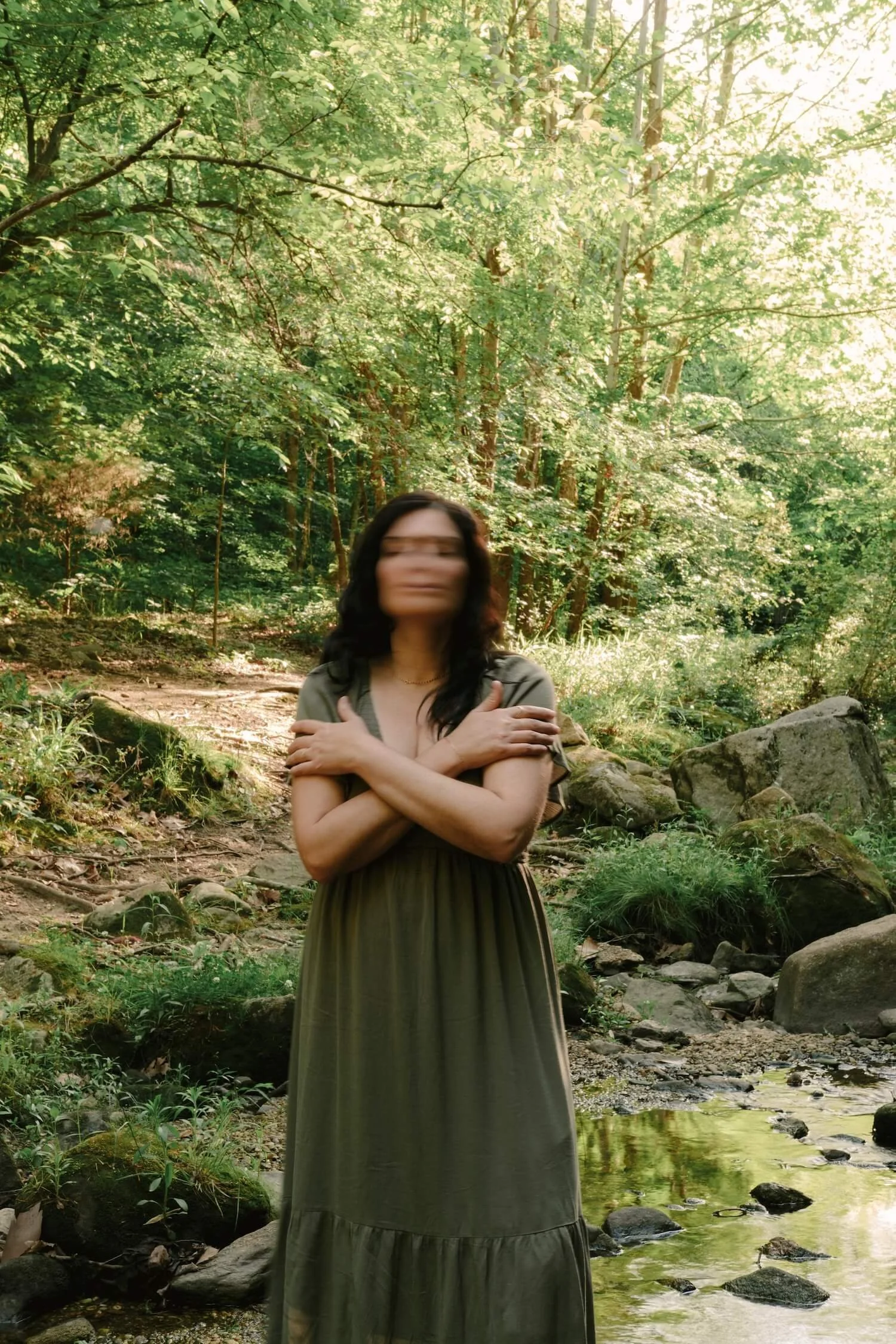 Kim Kimball, with her face gently blurred by movement, stands in a lush green forest for Life Transition Coaching.