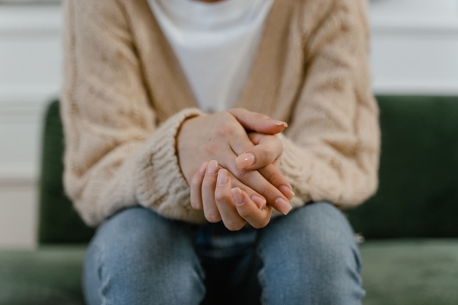 A woman sits with her hands clasped, reflecting on feeling stuck in life