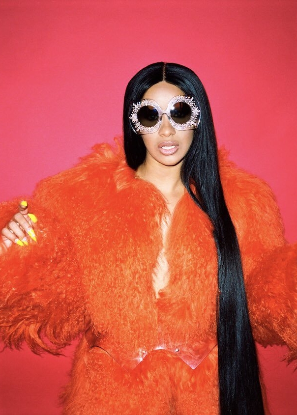 Cardi B posed for Paper Magazine wearing a bold orange fur by Jennifer Le and embellished Docle & Gabbana sunglasses.