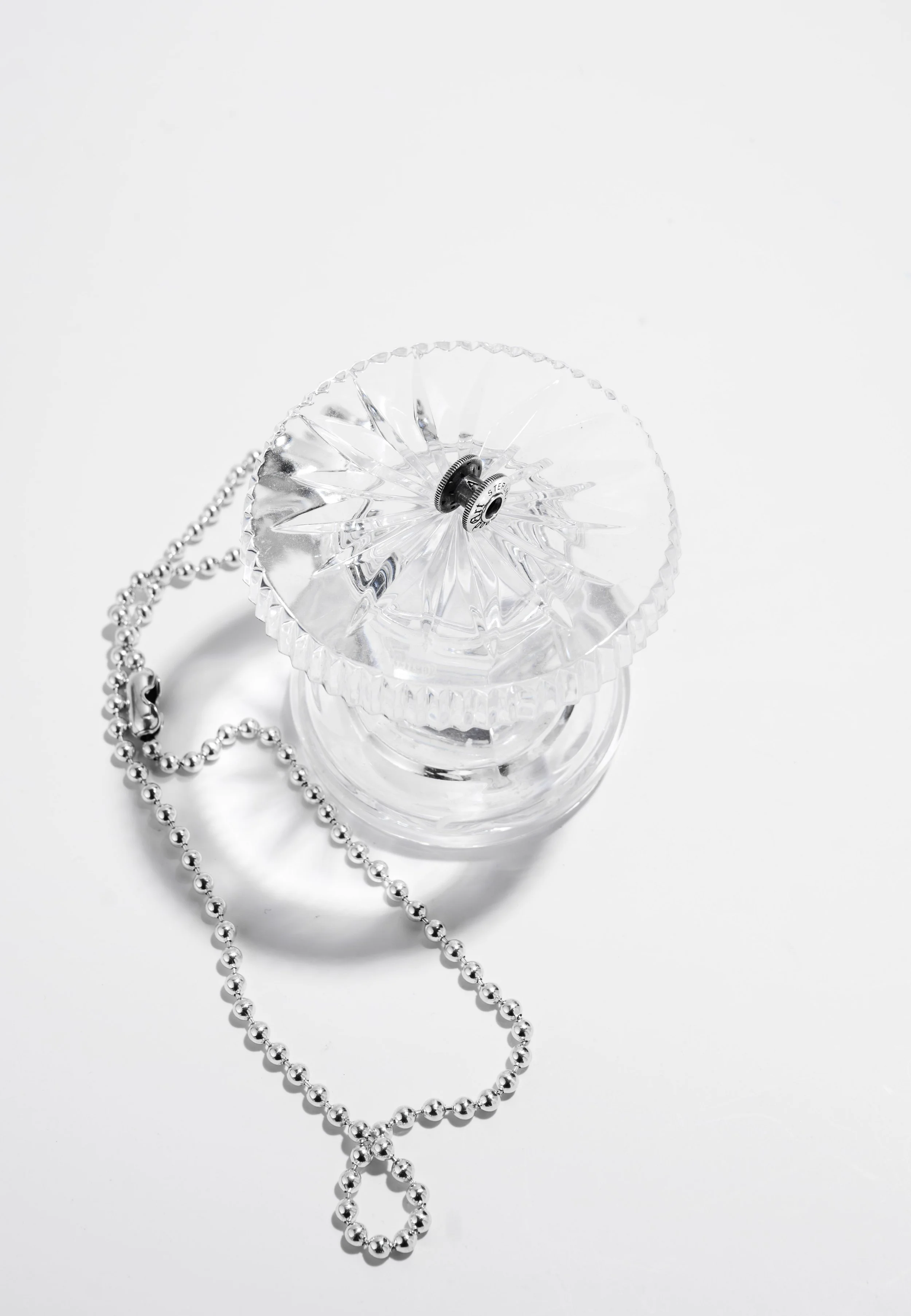 Good Art sterling silver ball chain necklace styled with a glass vessel — commercial product photography by Daniel Ponce, San Francisco