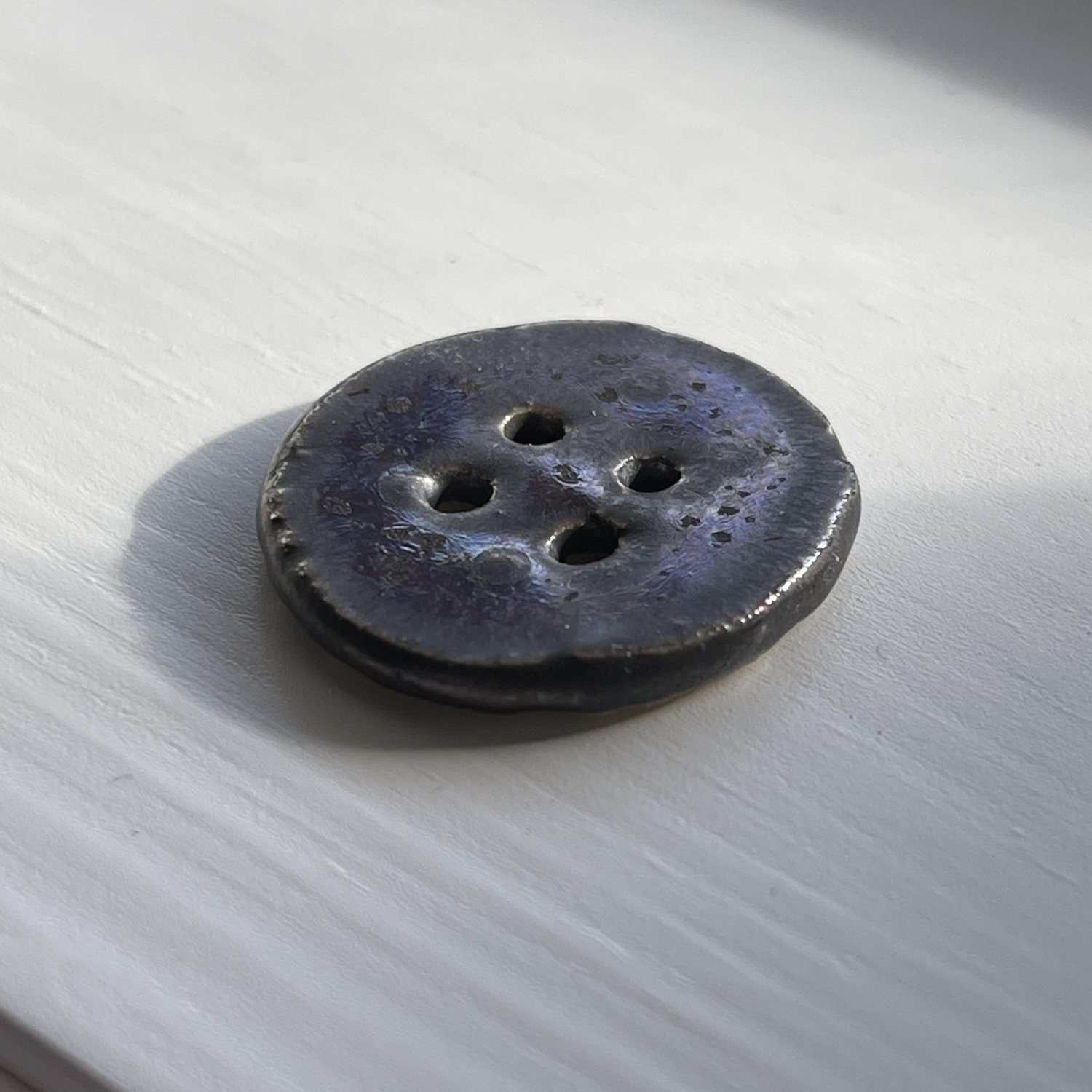 Stor knapp i keramikk med fargespel i overflata