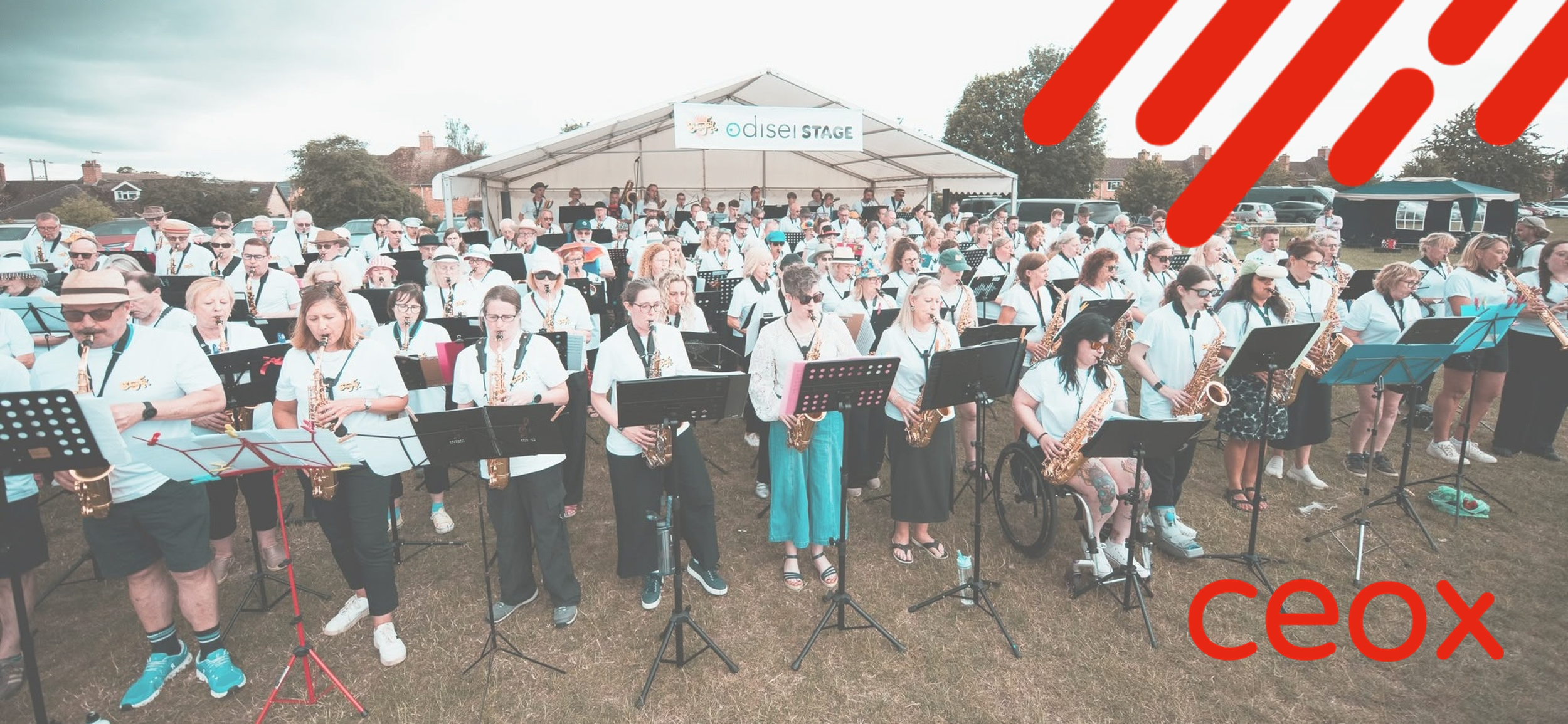 The Sax Bandits band performing at SaxoFest on a grass area in front of a small stage.
