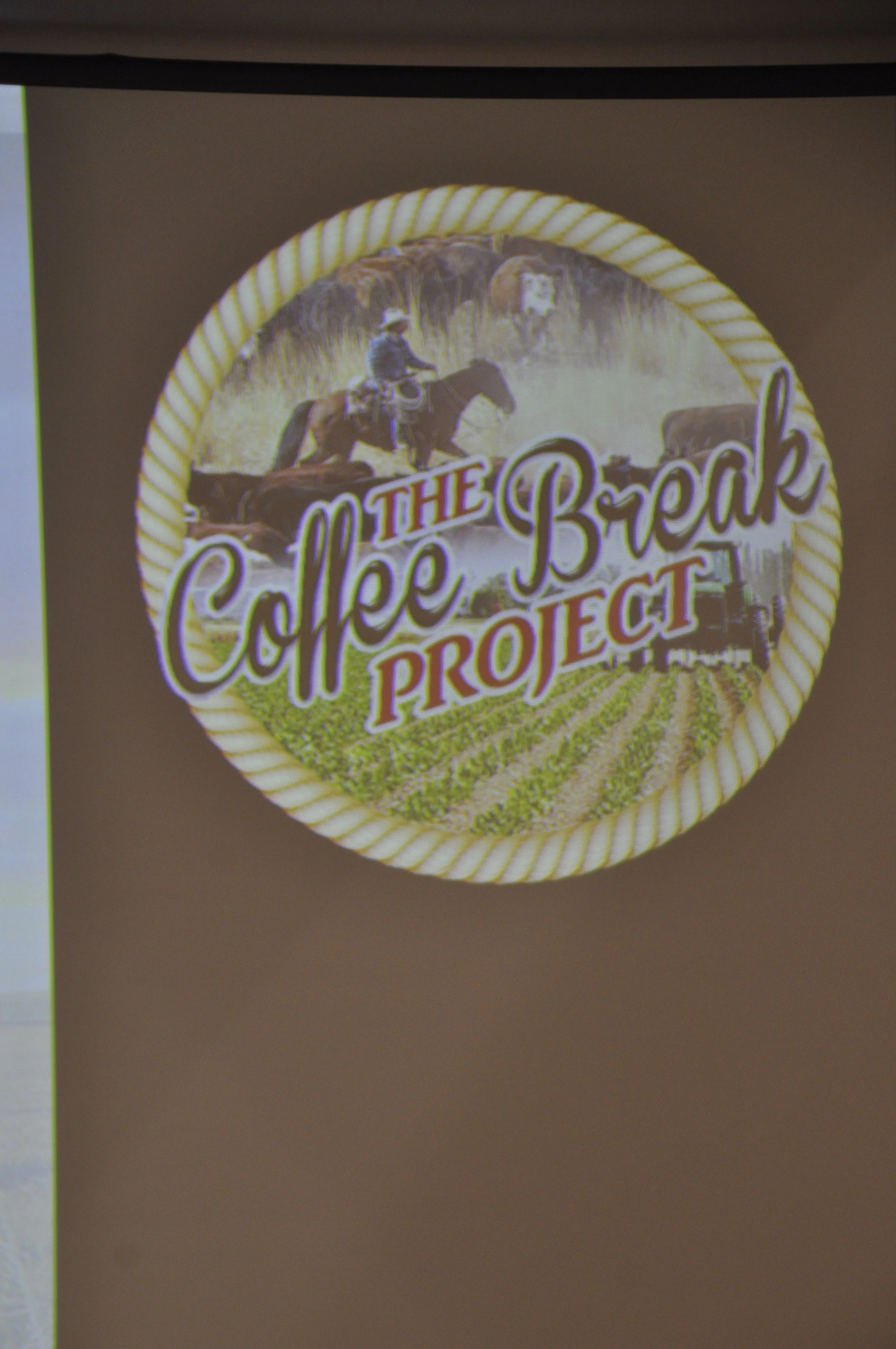 A circular sticker with a yellow and white twisted border, featuring an illustration of a person riding a horse and the text 'The Coffee Break Project'.