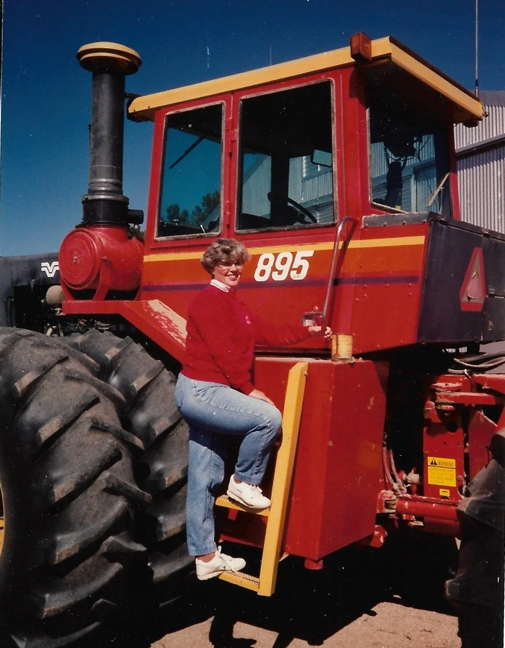 Woman in red sweatshirt climbing a red tractor