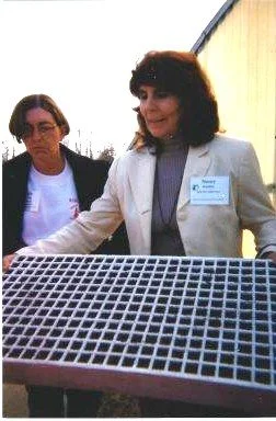 .  Nancy Koehler holding a tray of tobacco seedlings with Barb Riege watching