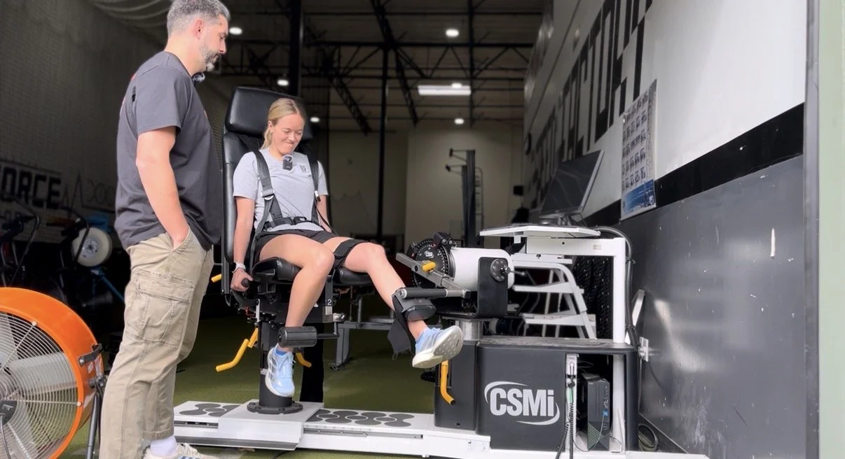 A physical therapist performing a movement assessment on an athlete in a modern clinic setting]