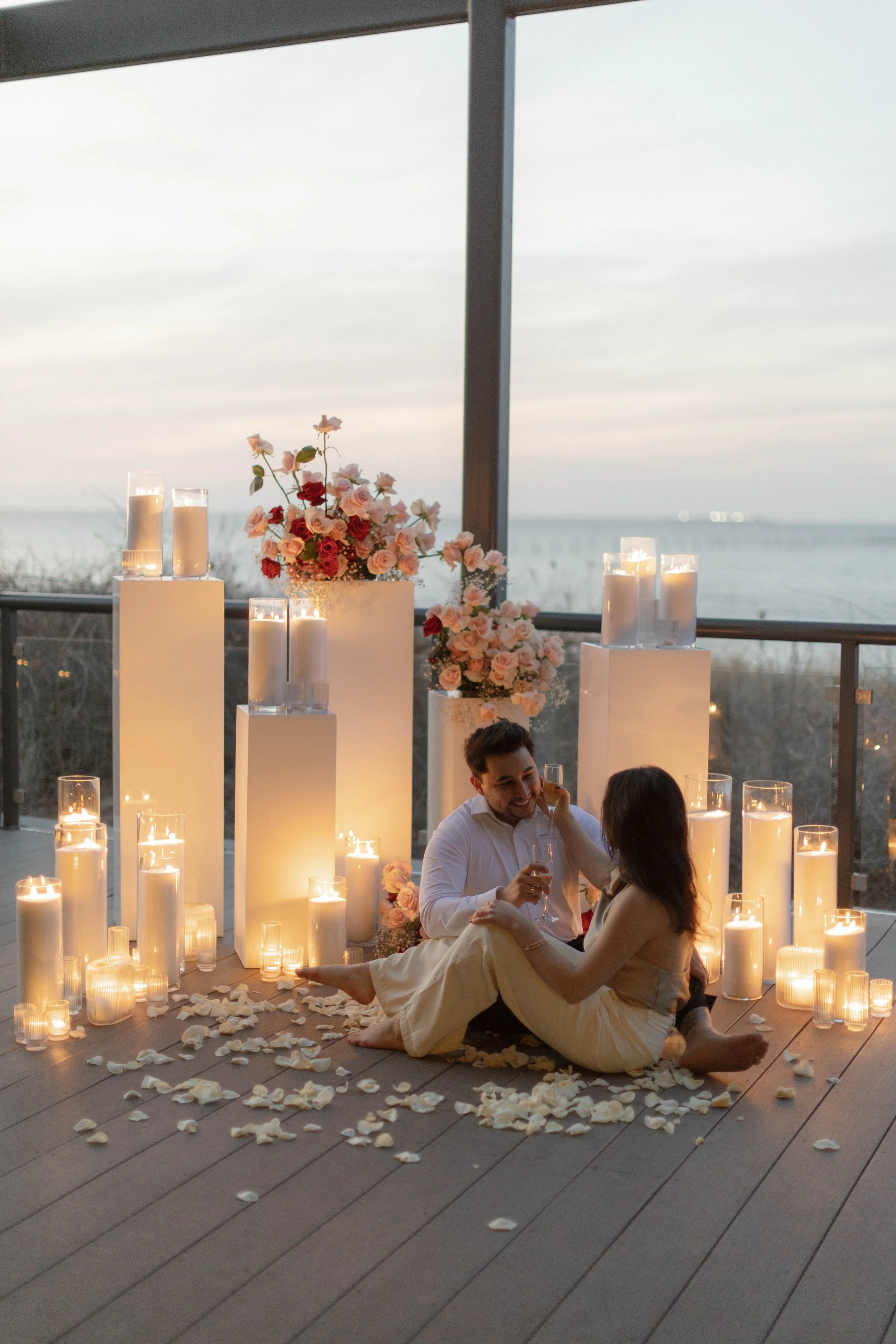 Candle-lit engagement proposal in Virginia Beach featuring a dramatic display of florals and candles overlooking the ocean