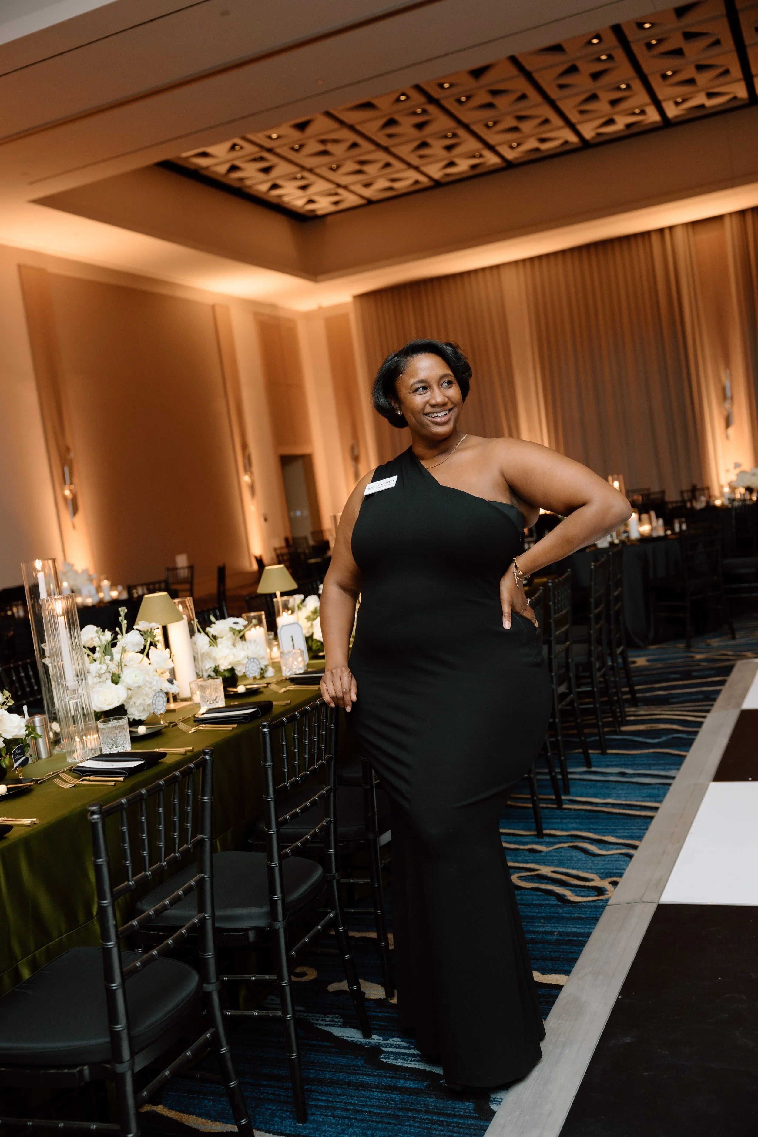 Professional wedding planner from By Love Events at elegant ballroom reception setup with olive green linens and white floral centerpieces